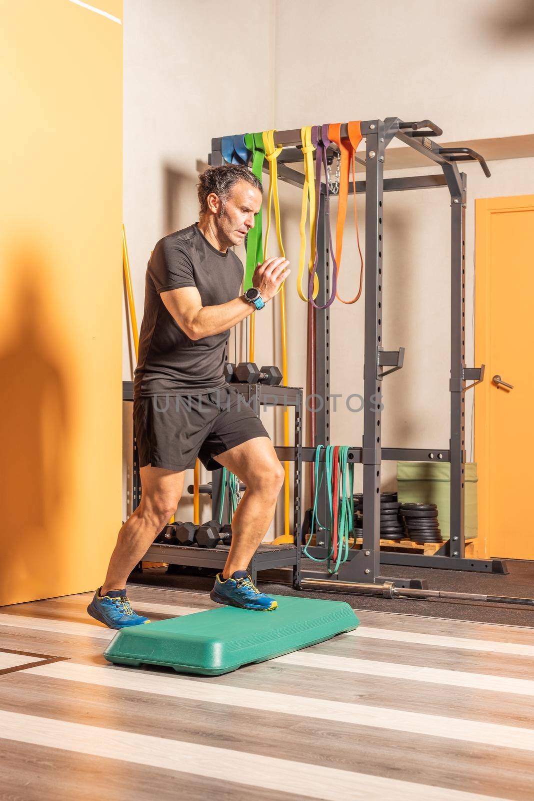 Sportsman doing step up jumps in health club. Concept of exercises with equipment in health club.