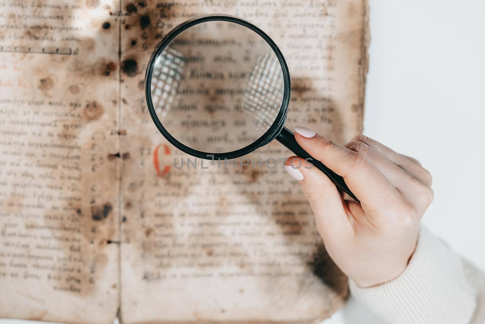 Woman researcher explores antique book with magnifier. Scientific translation of literature. Investigating manuscript with ancient writings. High quality