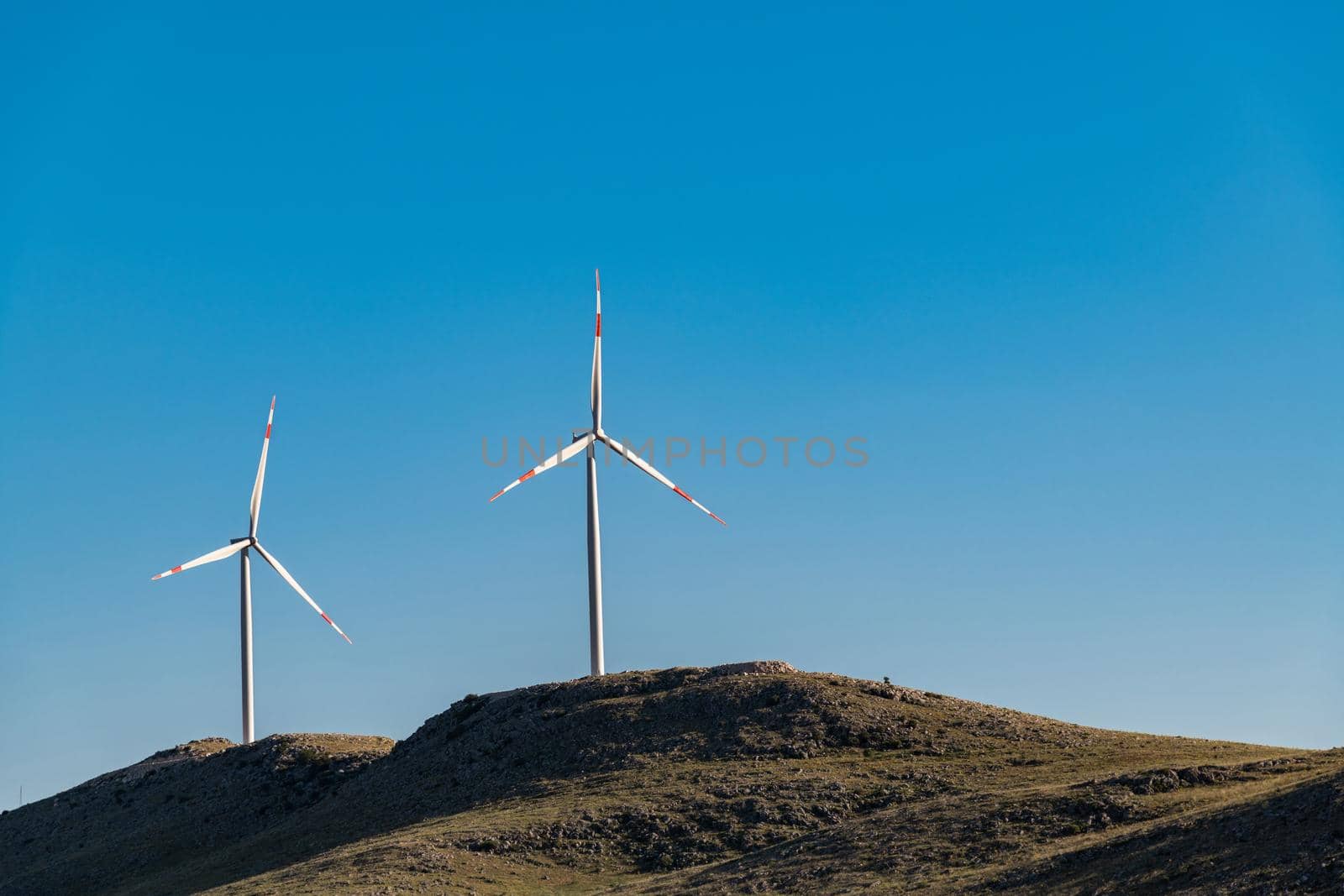 clean electricity producing wind turbine or windmill built on a windy mountain ridge