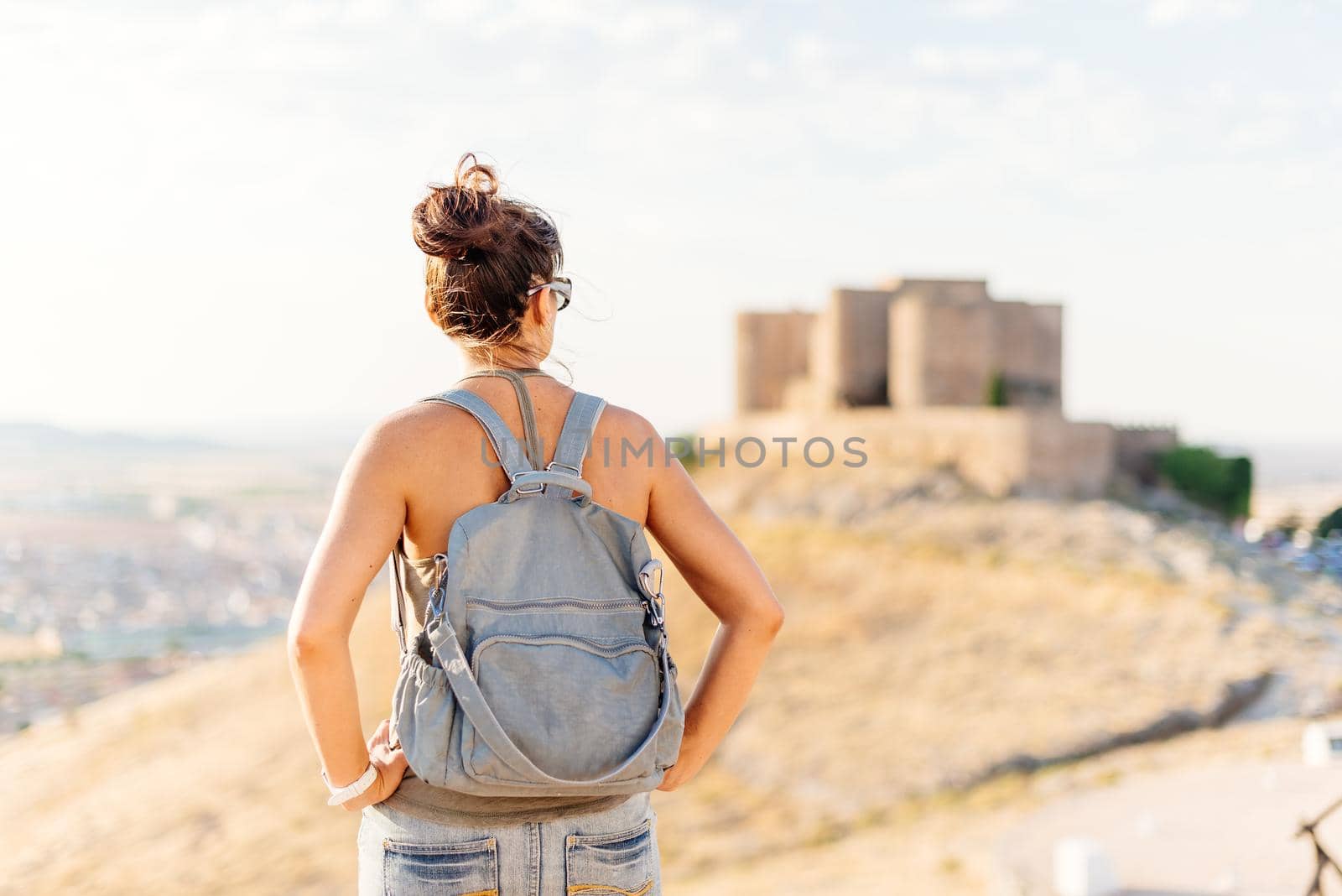 Woman in summer clothes standing and looking at a medieval castle by ivanmoreno