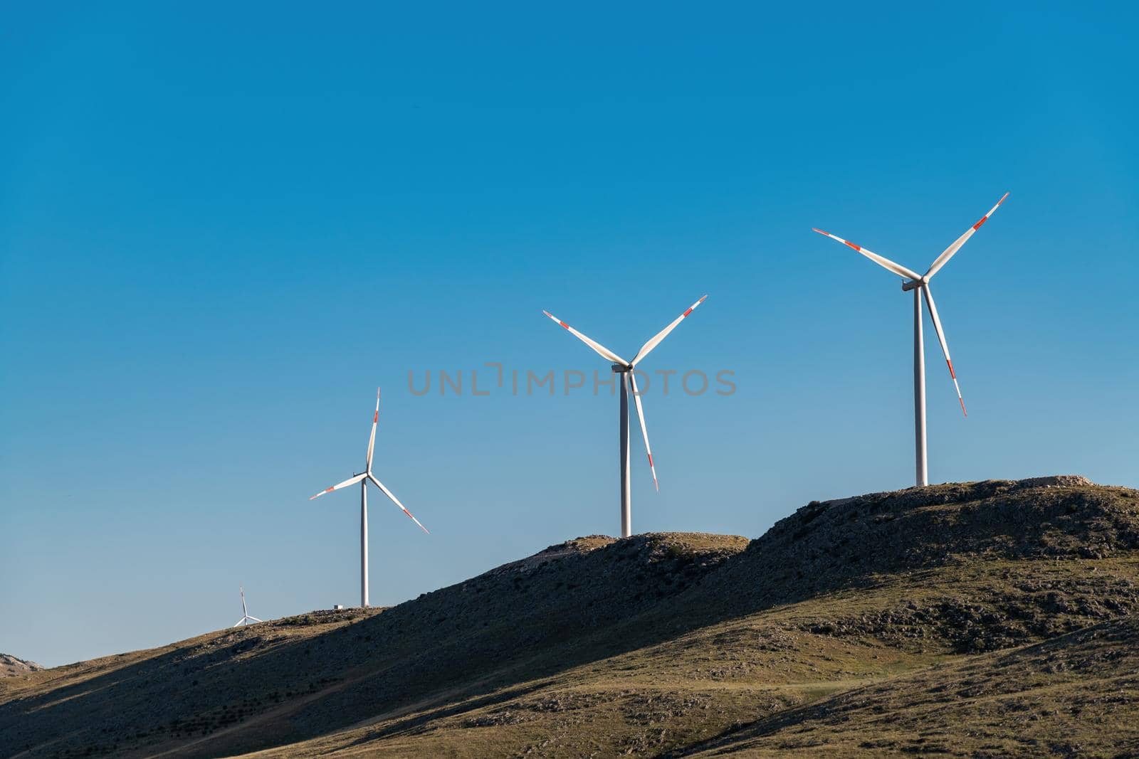 clean electricity producing wind turbine or windmill built on a windy mountain ridge