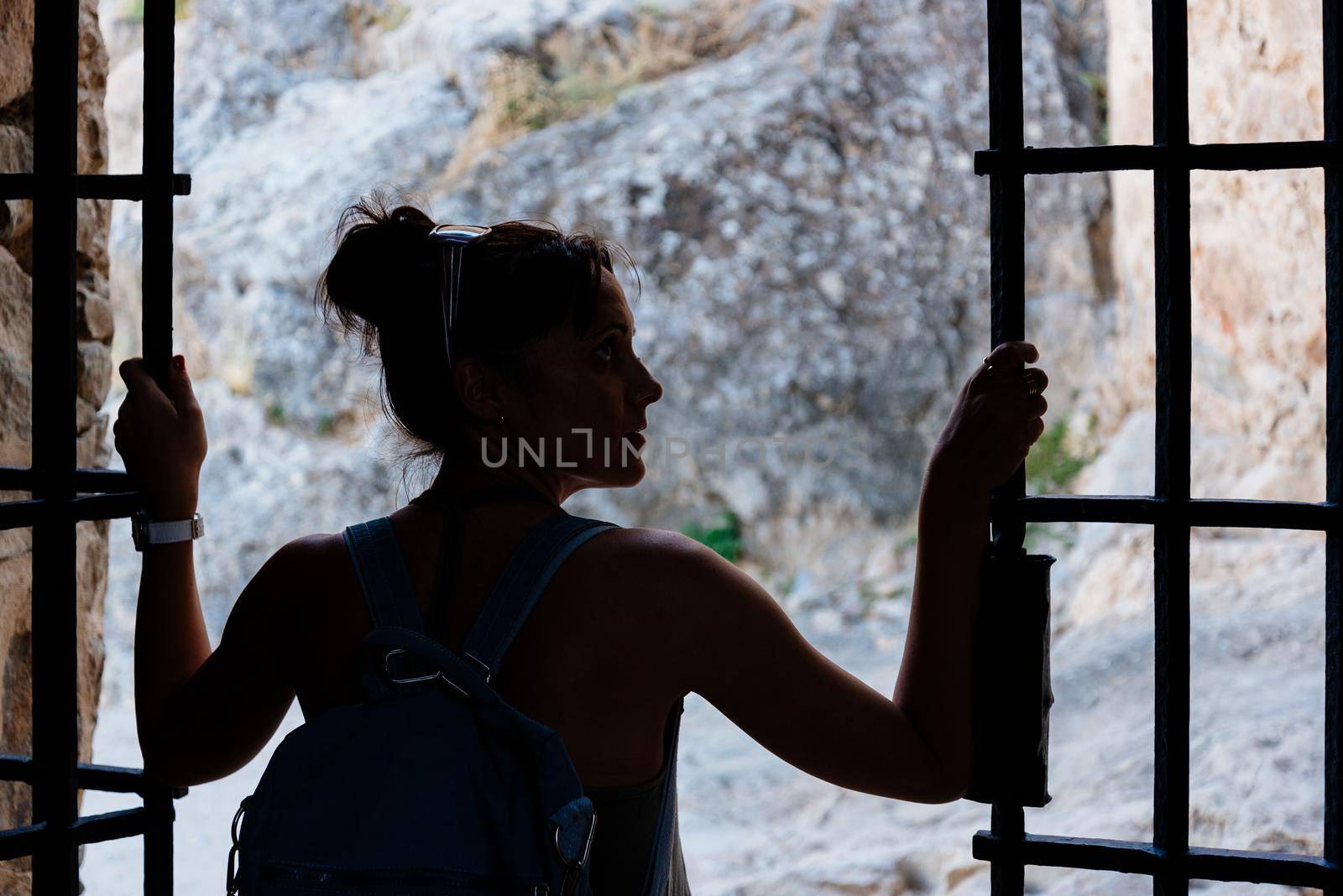 Silhouette of a woman in shadow opening a metal door of a medieval castle by ivanmoreno