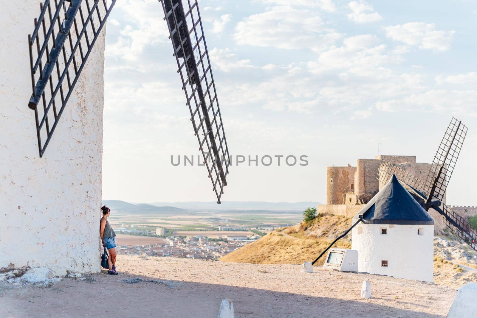 Woman leaning against the facade of a windmill while contemplating the landscape by ivanmoreno