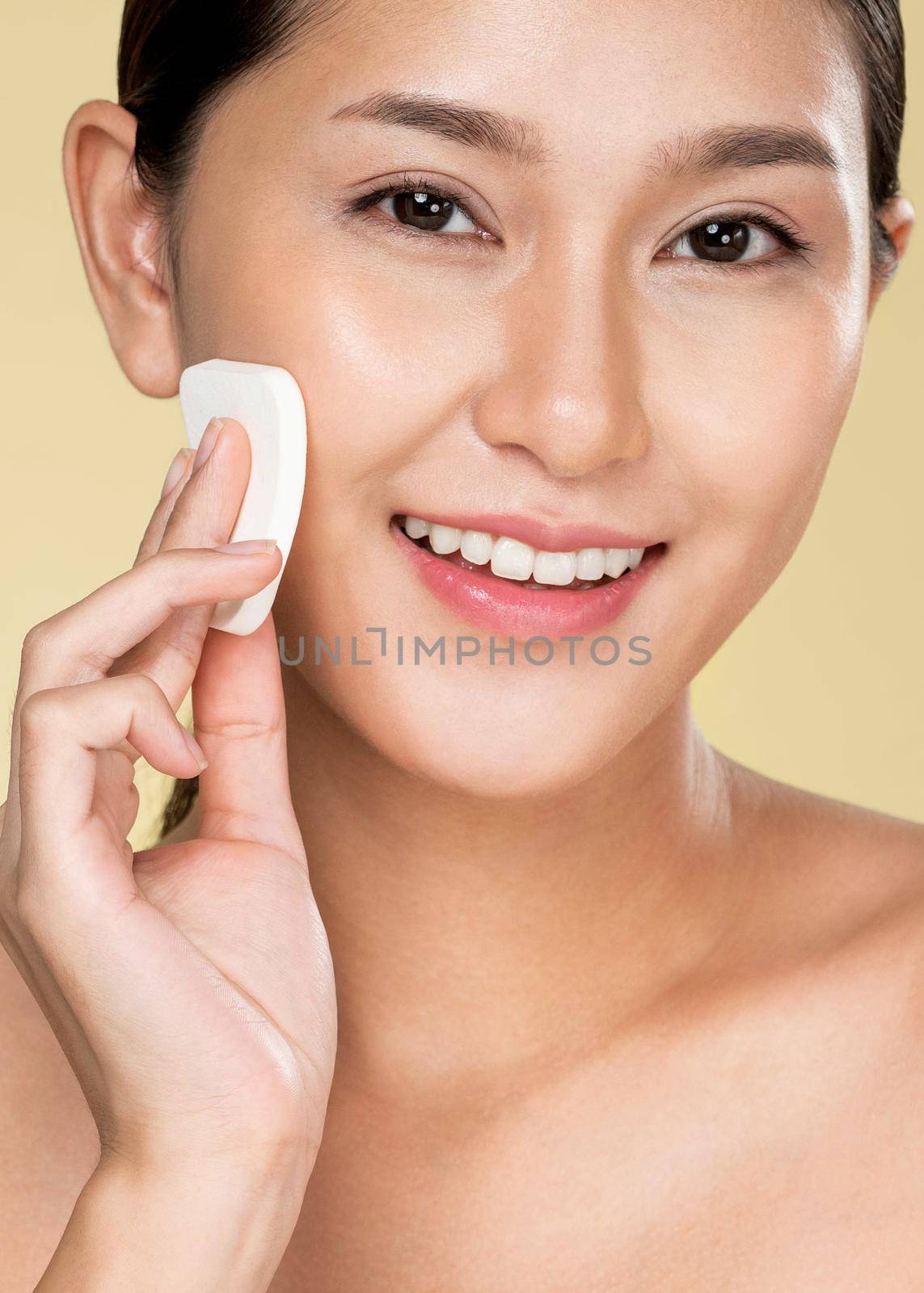 Closeup ardent woman applying her cheek with dry powder and looking at camera. Portrait of younger with perfect makeup and healthy skin concept.