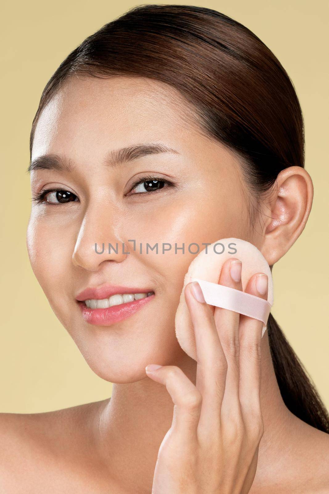 Closeup ardent woman applying her cheek with dry powder and looking at camera. Portrait of younger with perfect makeup and healthy skin concept.