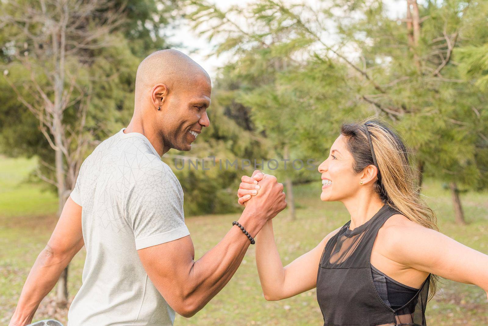 Close up of an ahlete couple exercising by holding with one hand in the park by ivanmoreno