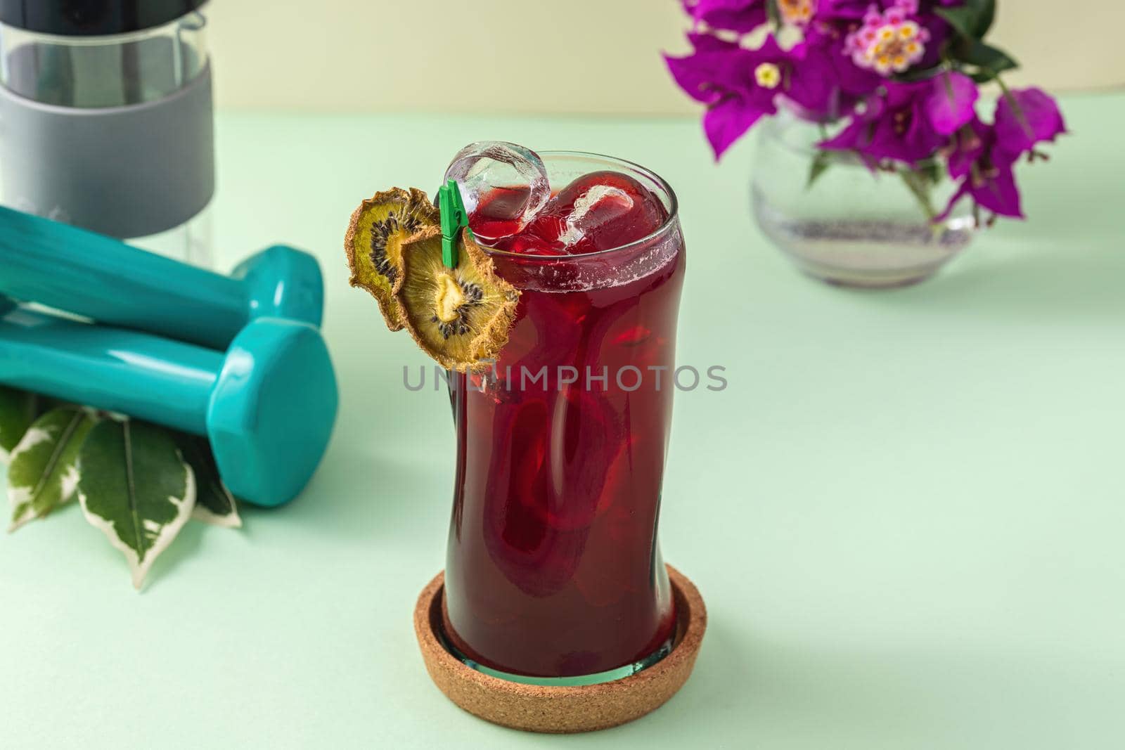 Refreshing healthy drink in long glass cup on light green background