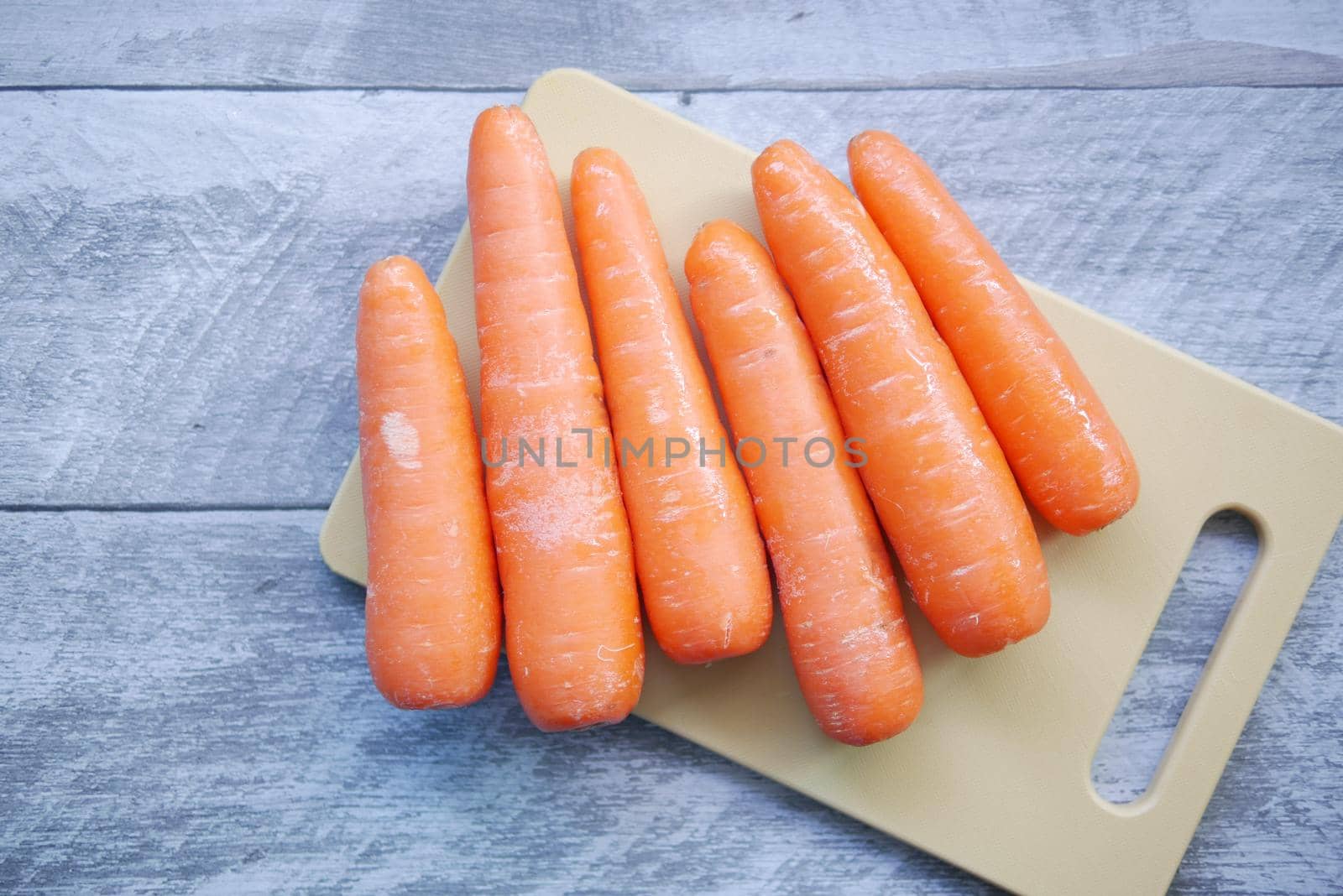 fresh carrots on chopping board on table .