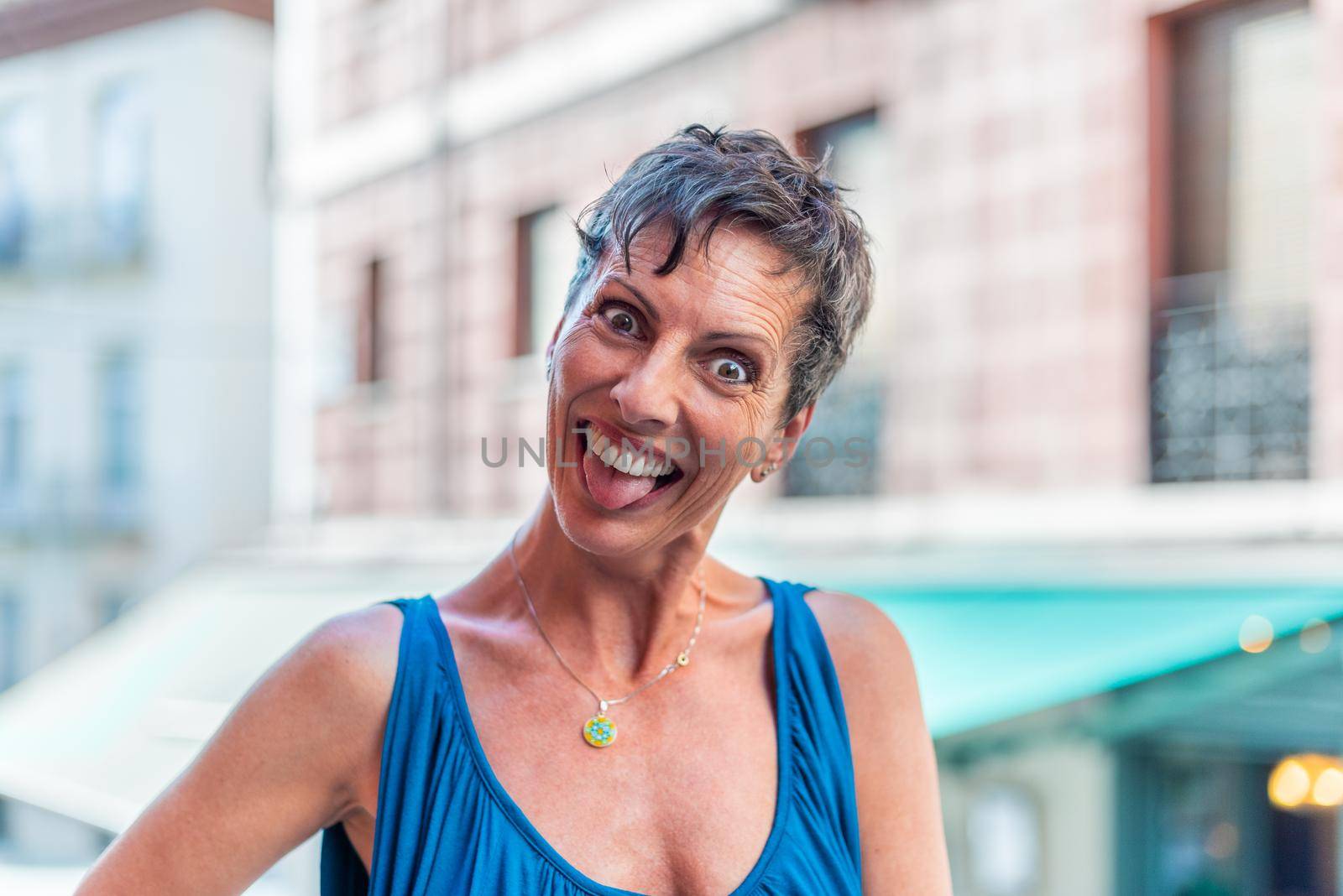 Portrait of a funny short hair mature woman on the street doing funny faces. Middle aged woman in the city having fun.