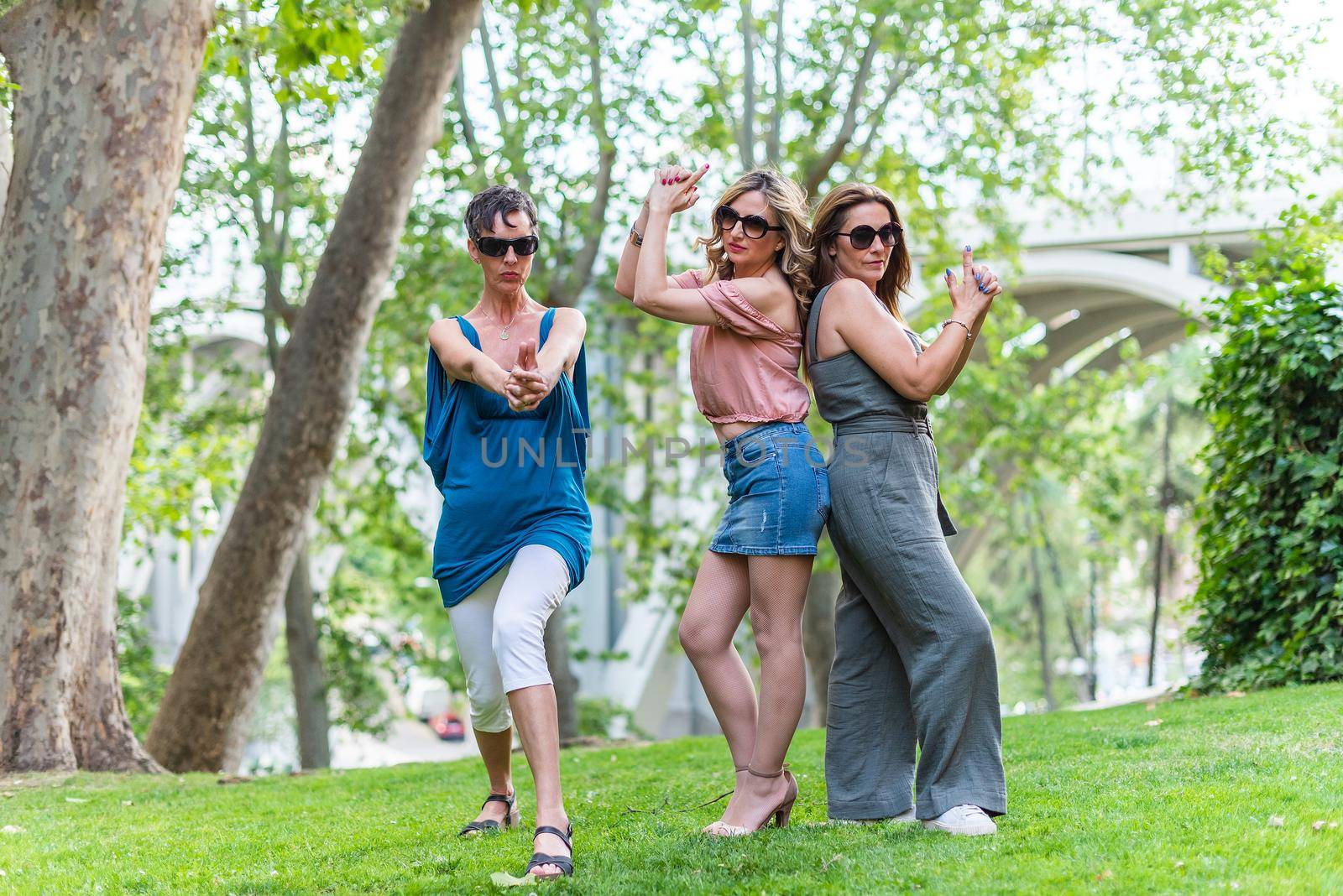 Three mature female friends making a pistol gesture with their hands and posing. by ivanmoreno