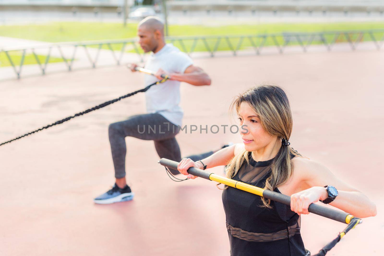 Fitness people exercising with an elastic gym stick in the park. Multi-ethnic people exercising outside.