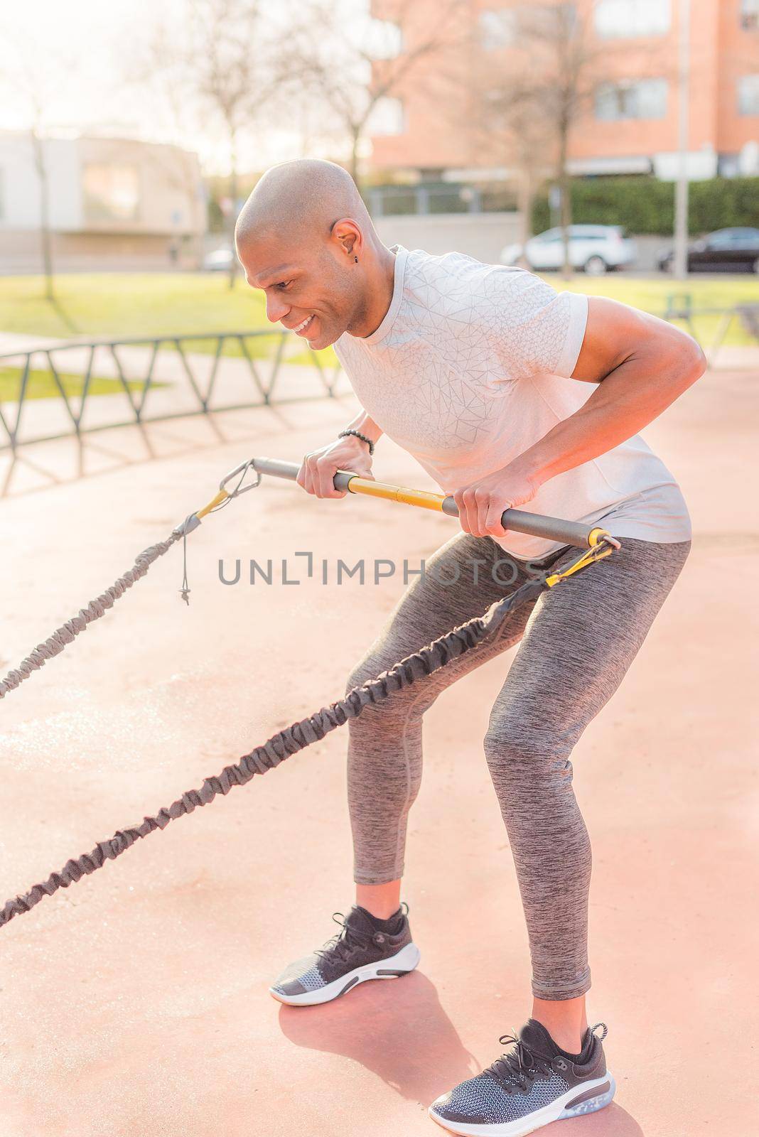 Side view of an atlhetic latin sportsman exercising with an elastic gym stick in the park by ivanmoreno