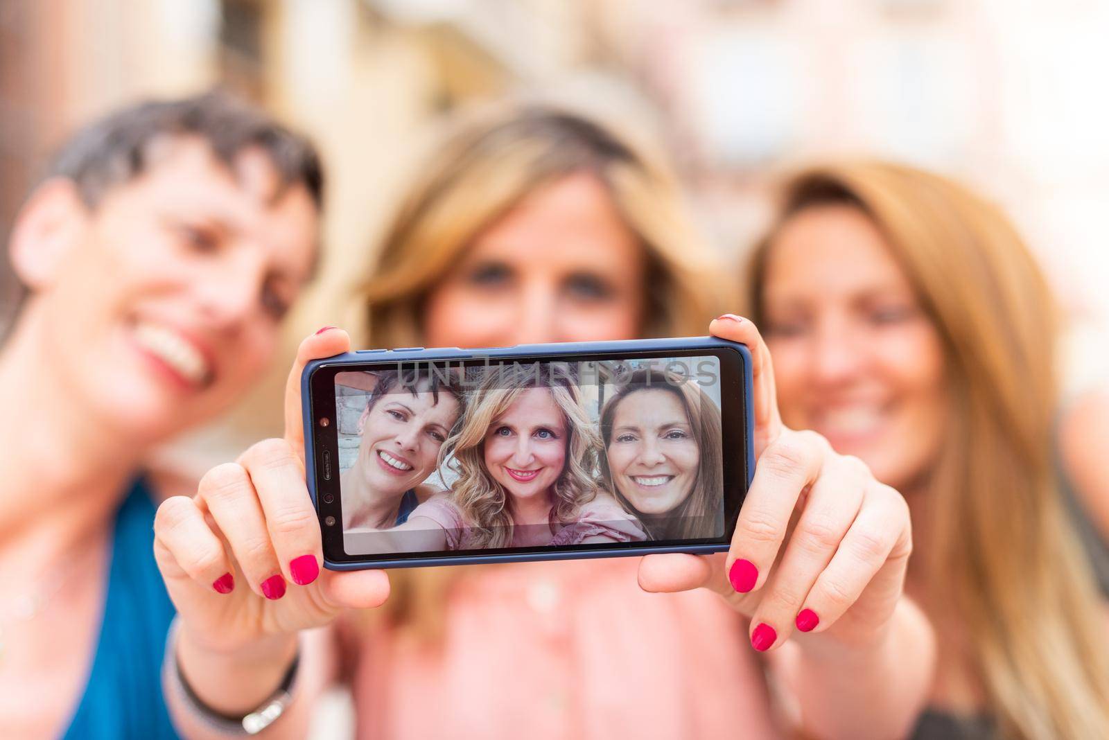 Three mature female friends taking a selfie horizontally. Middle aged friends sharing time together and having fun.