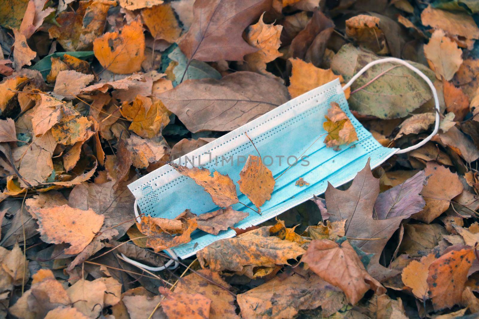 A used medical mask lies in yellow fallen leaves. The concept of the fight against coronovirus. Protection against covid-19. The spread of the epidemic around the world