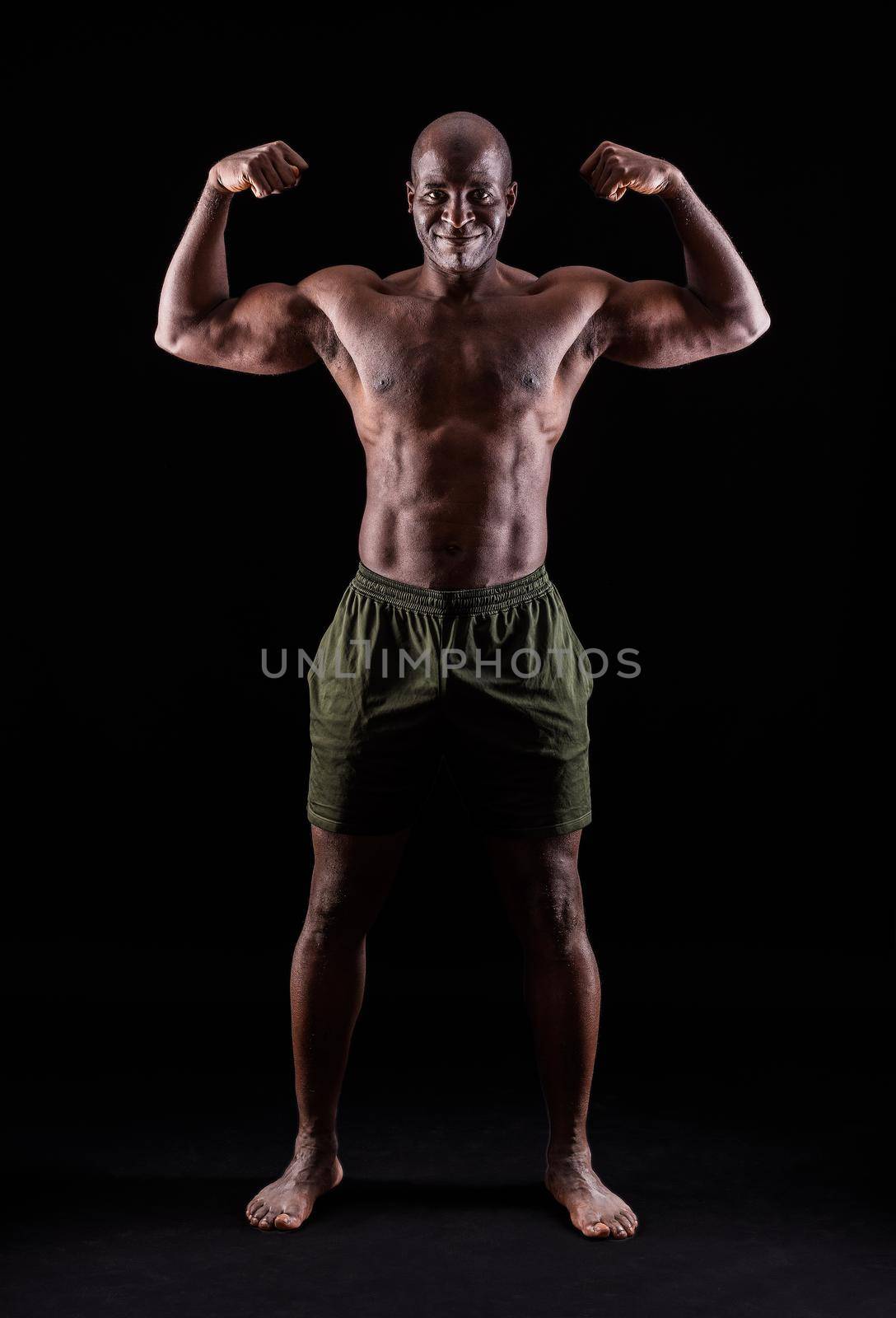 African American muscular man smiling flexing arm muscles on a black background by ivanmoreno