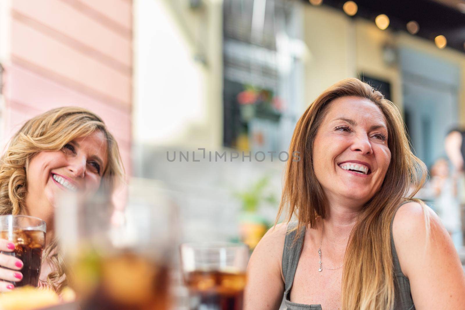 Middle-aged adult women in a cafe having drinks and chatting. Beautiful mature women having a good time together.