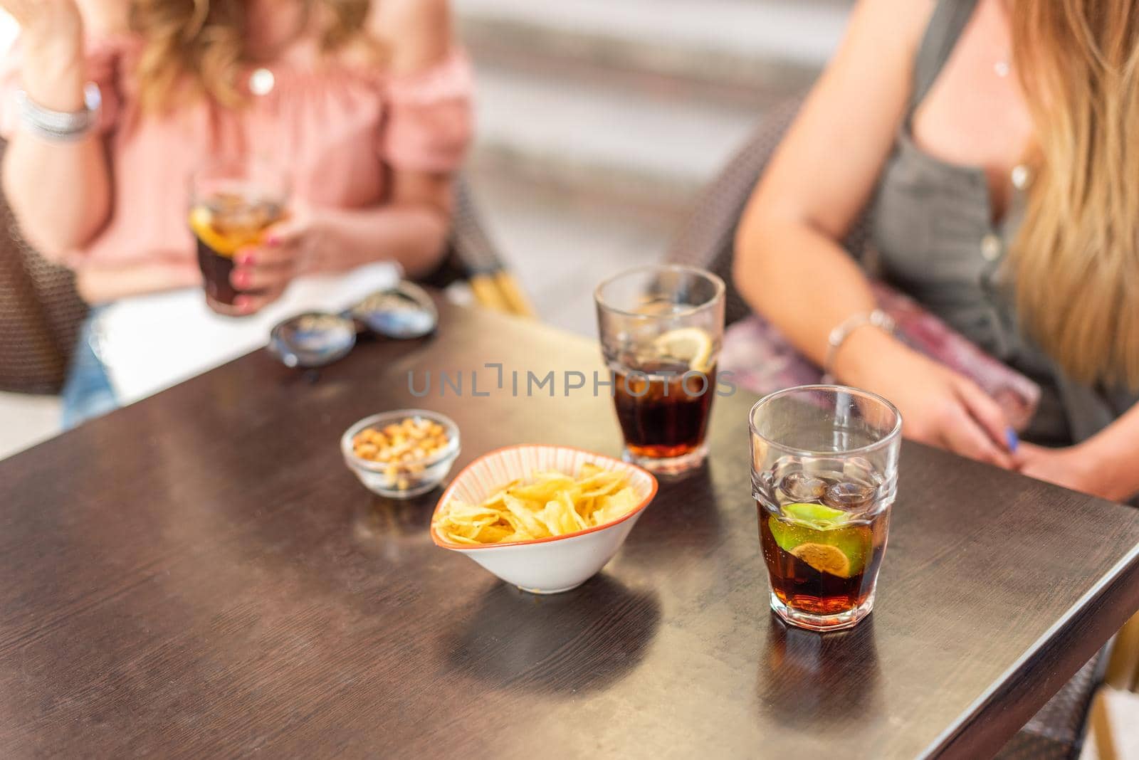 Cropped view of some drinks and snacks being consumed by adult friends. Mature women having a good time together.