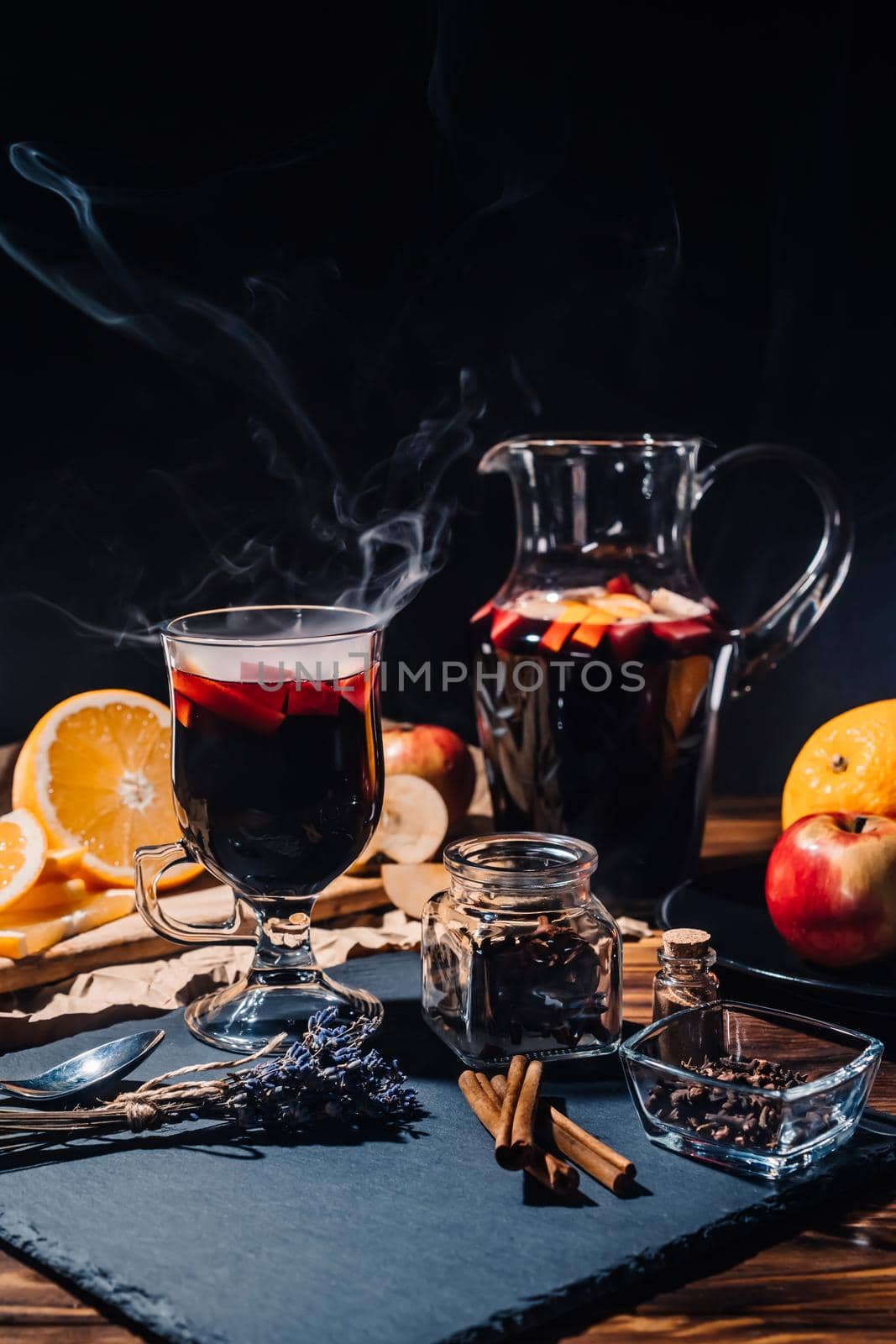 Stunning view of hot mulled wine with honey, fruits and spices. Fragrant atmosphere of Christmas winter holiday. Glass with cinnamon and orange on table.High quality