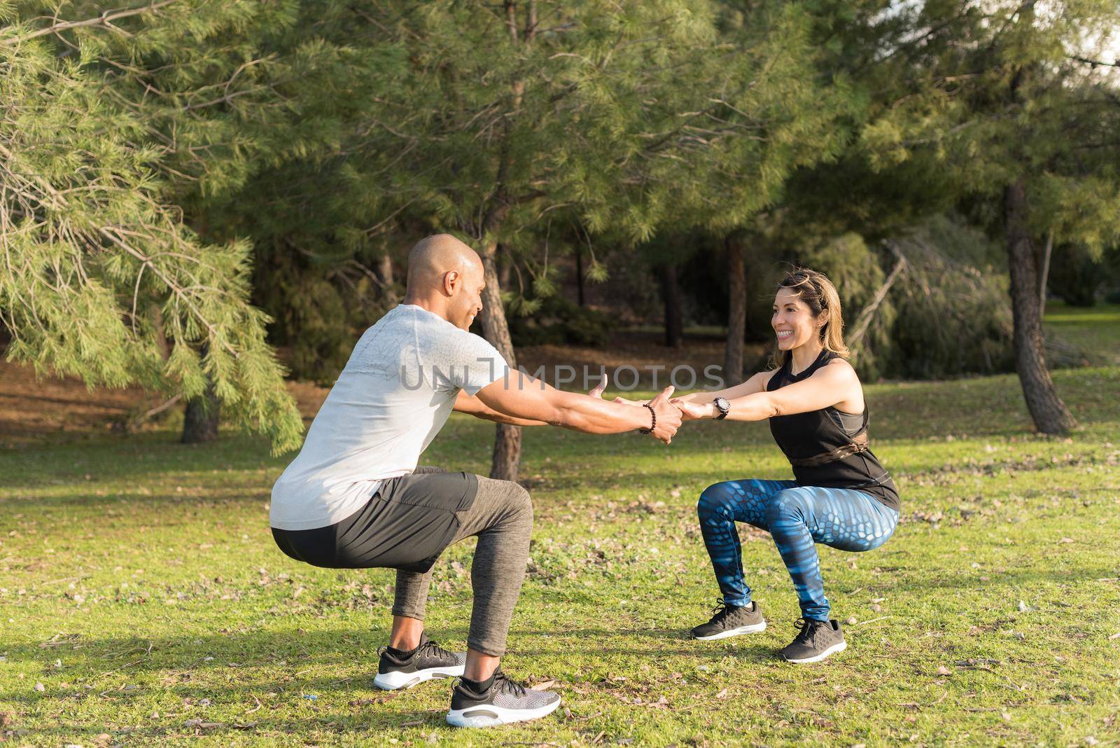 Fitness couple exercising by holding hands in the park by ivanmoreno