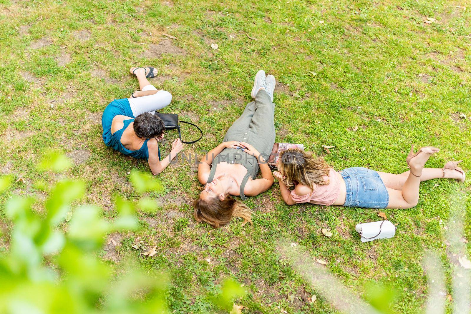 Middle-aged friends lying on the grass having a good time. Three mature friends having fun and having a good time together.
