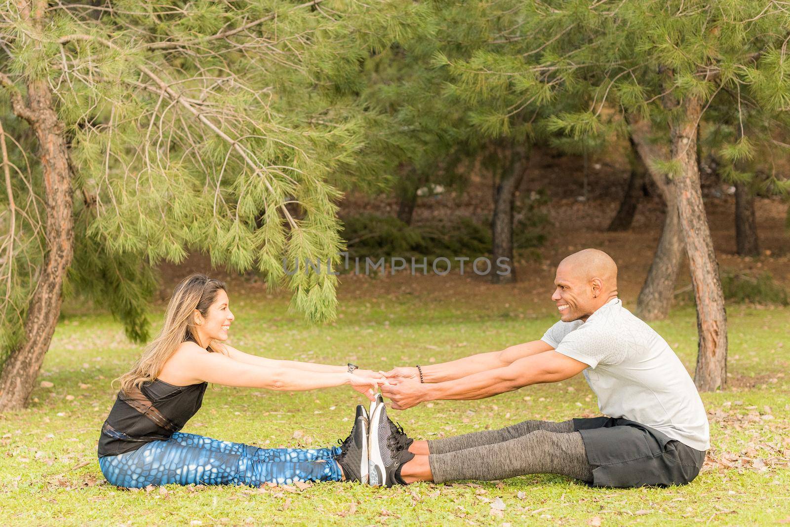 Sporty couple doing exercises together while sitting and holding hands by ivanmoreno