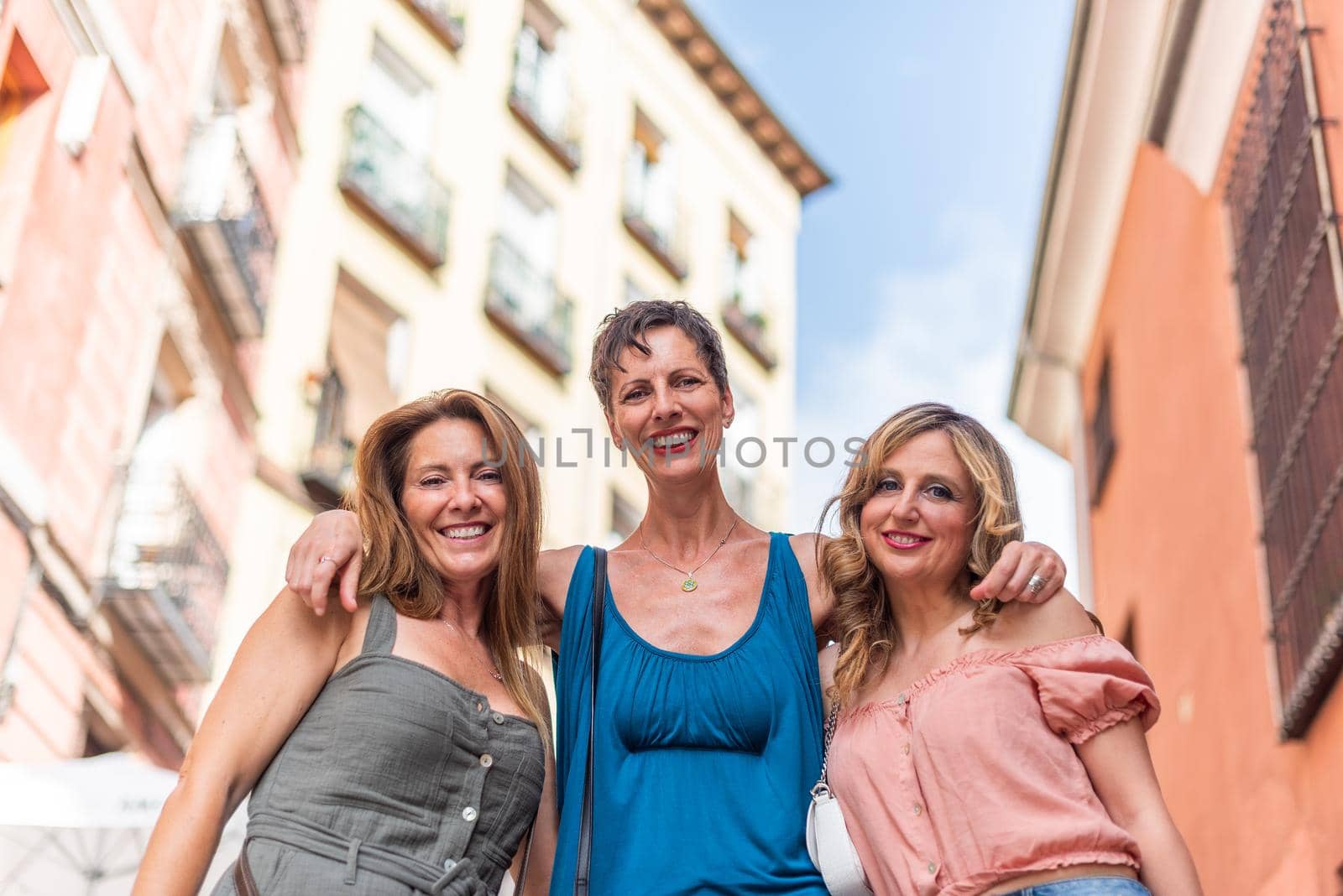 Three cheerful adult women hugging and looking at the camera. Beautiful mature women having a good time together.