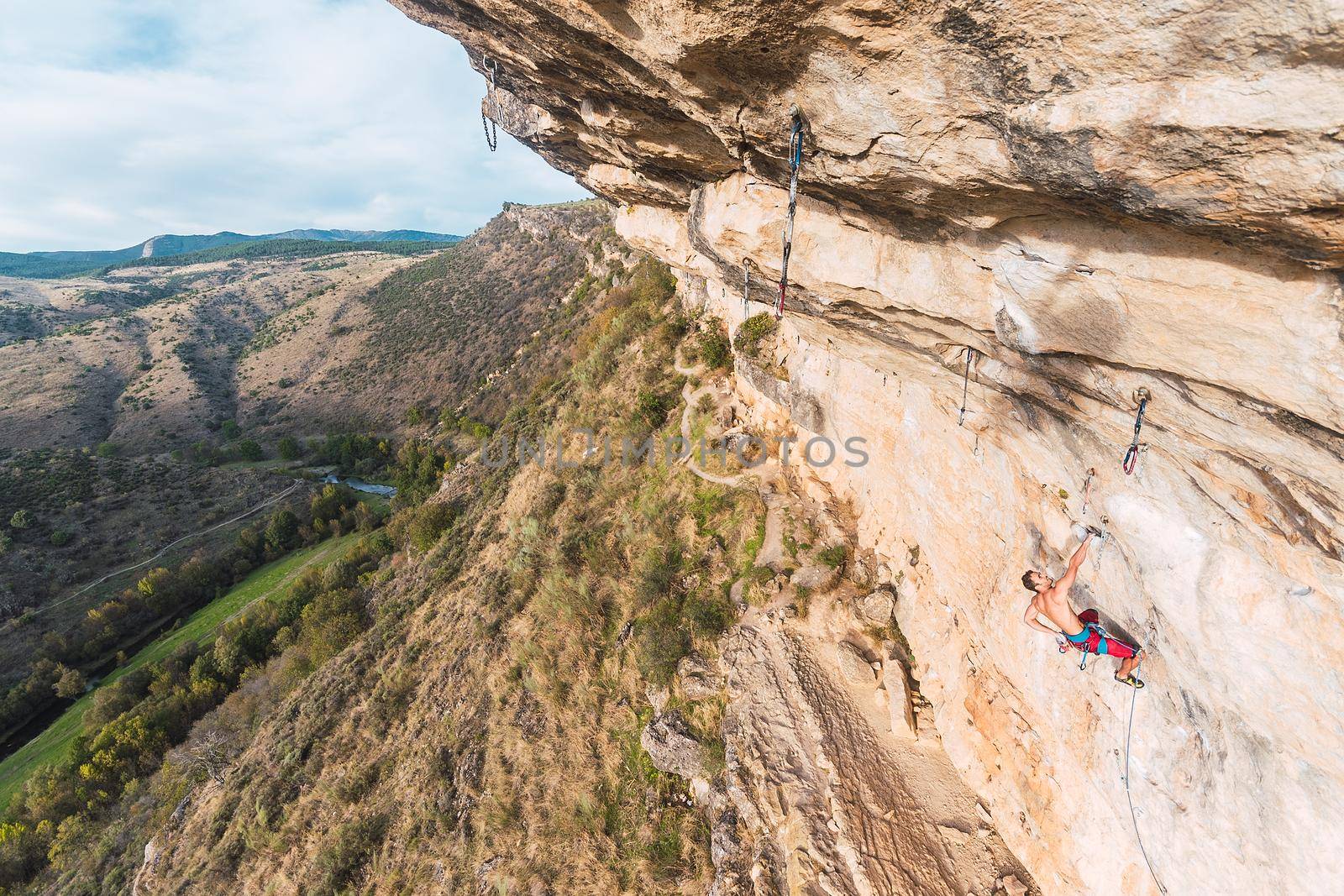 Aerial view of a rock climber holding on with one hand on rock by ivanmoreno