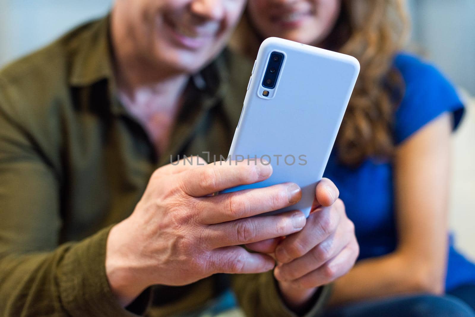 Detail of unrecognizable couple looking at the mobile smiling. High quality photo