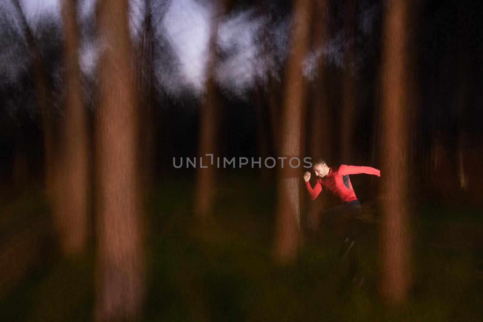 Man running through the trees on a blurred motion of forest. Nature abstract background.