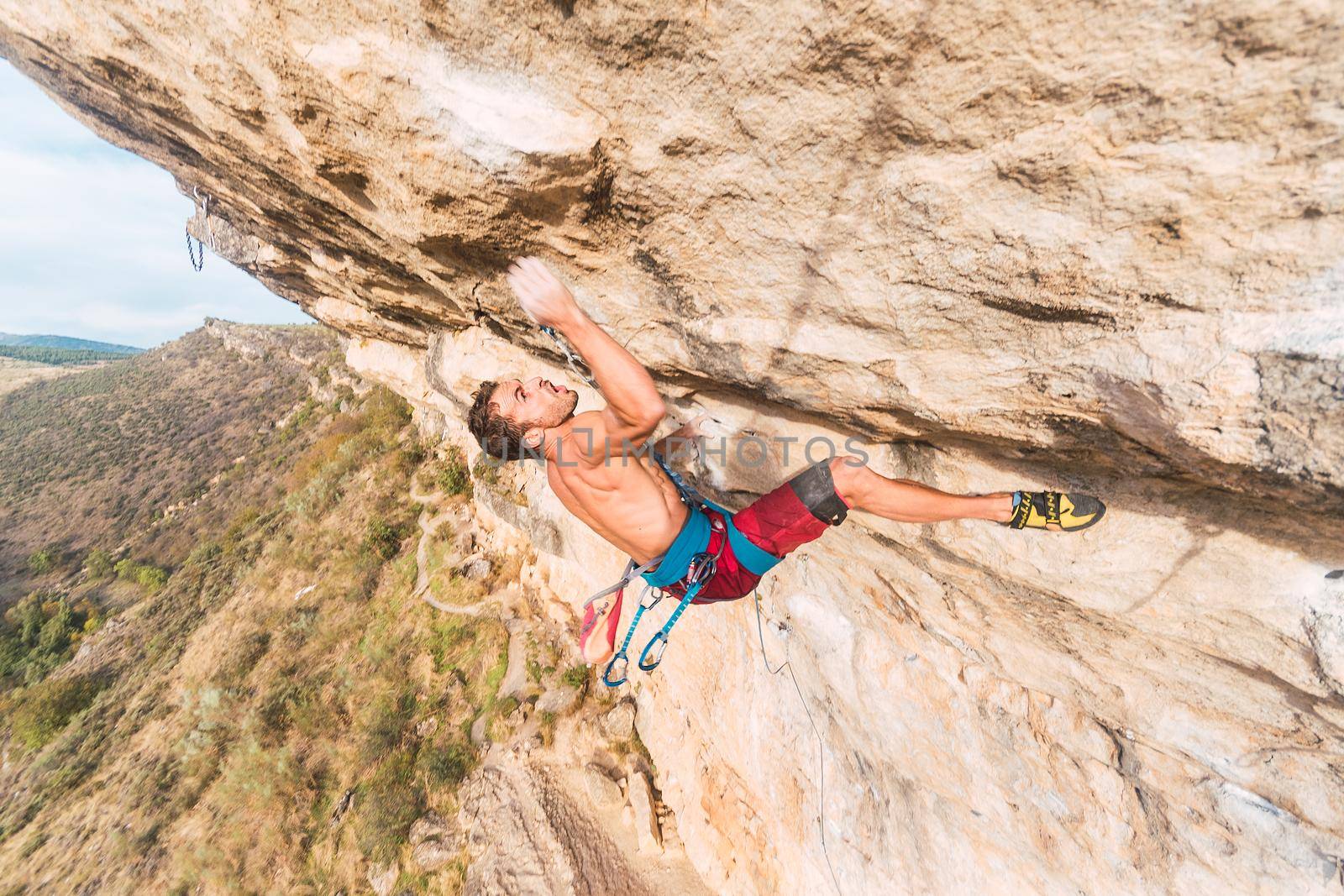 Male climber making an effort to continue climbing. Excited climber in action.