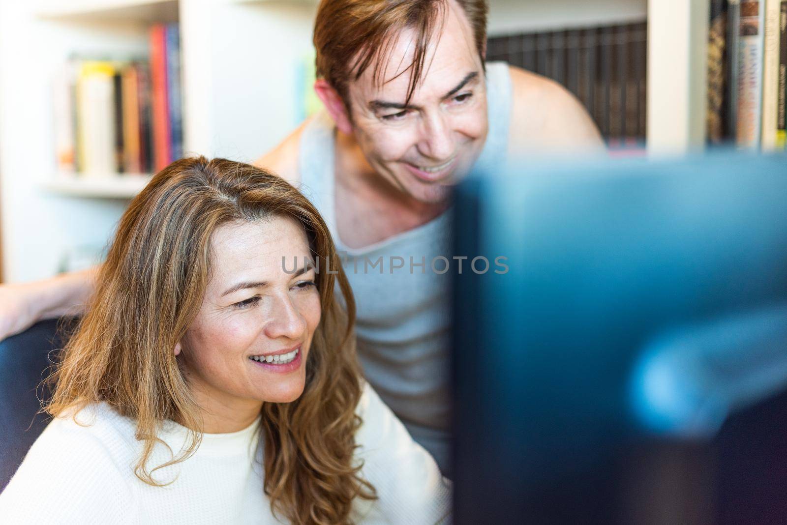 Middle-aged couple looking happy at computer at home. High quality photo