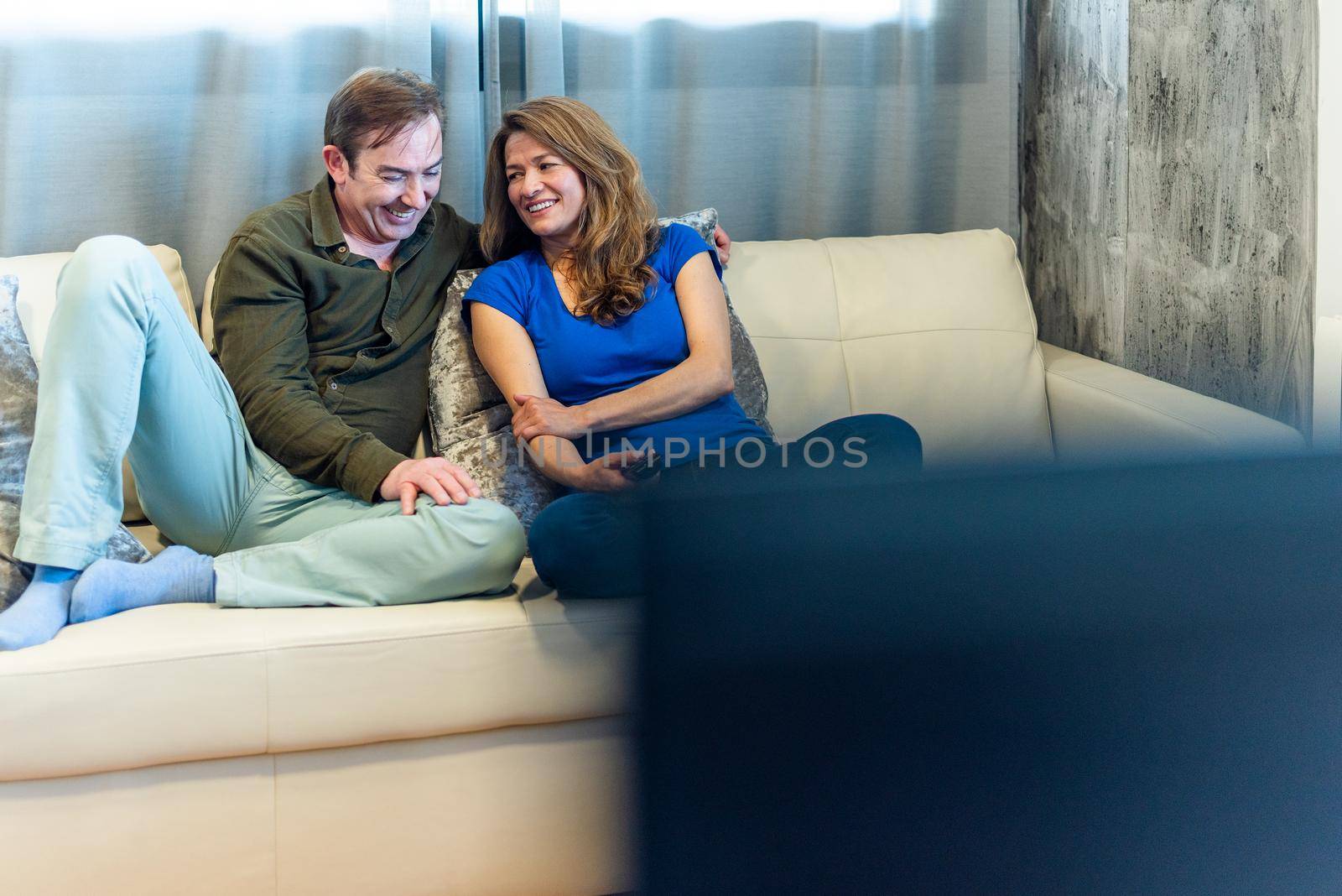 Mature man and woman on the couch watching a movie. High quality photo