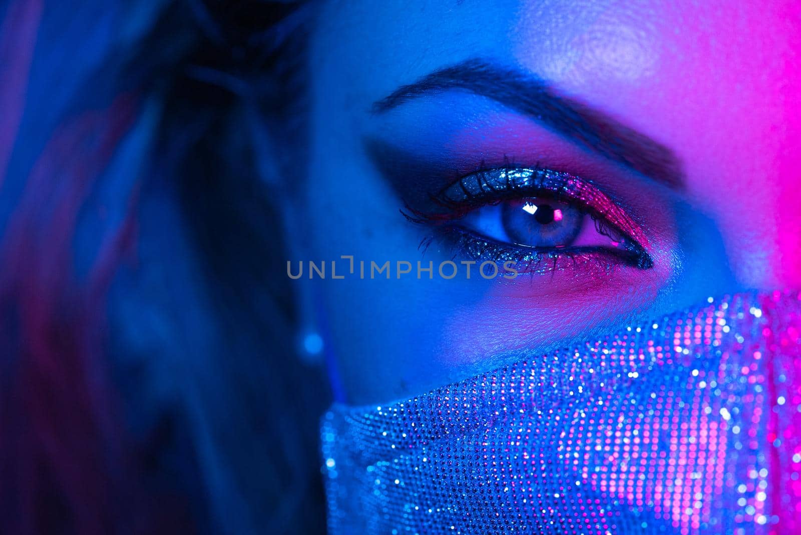 Close up of face in glitter protective mask, amazing make-up. Eye under neon light. Female with shining shadows and false lashes. Nightlife, night club, pandemic, covid-19 concept. High quality photo