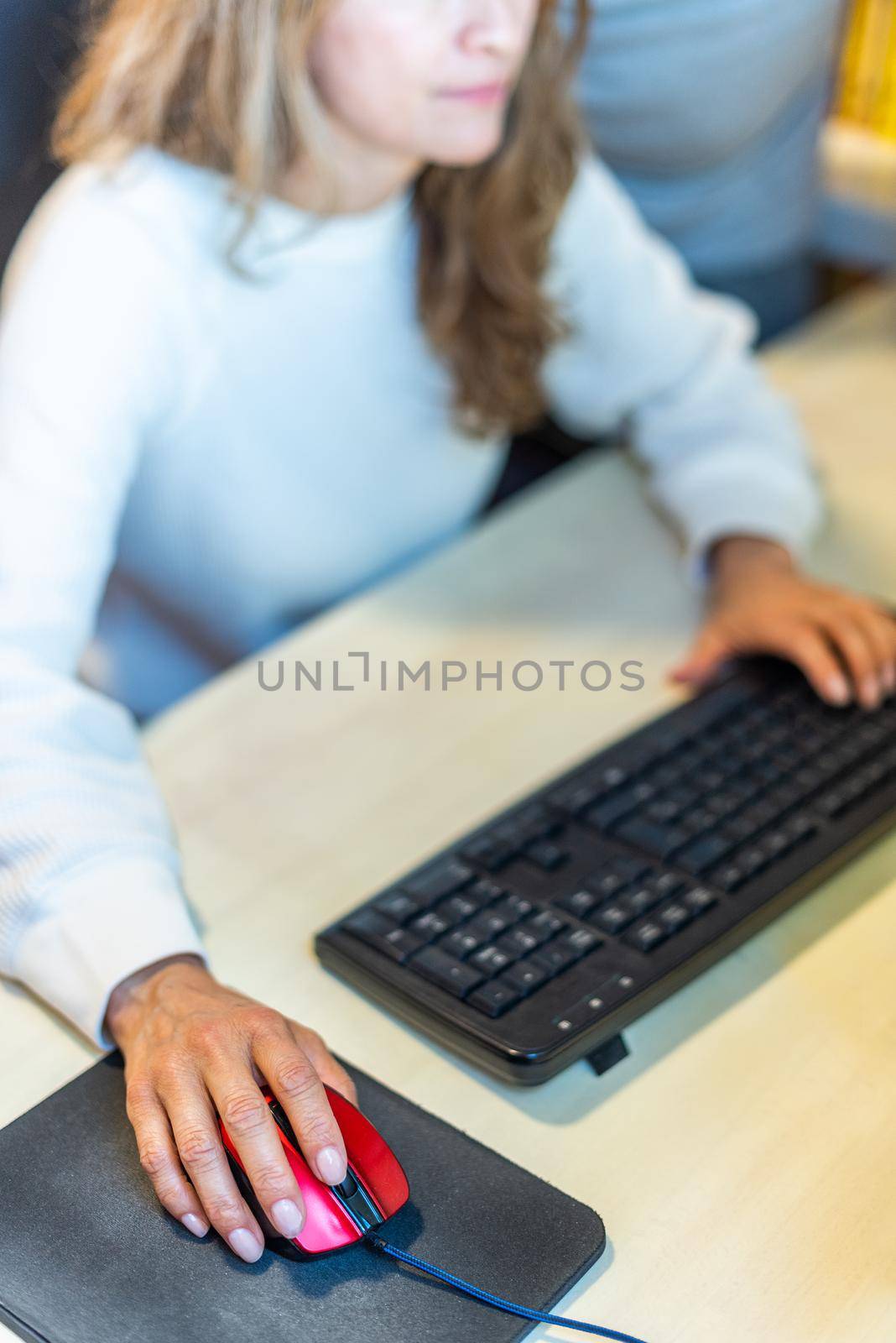 Detail of unrecognizable woman working in front of the computer moving the mouse. High quality photo