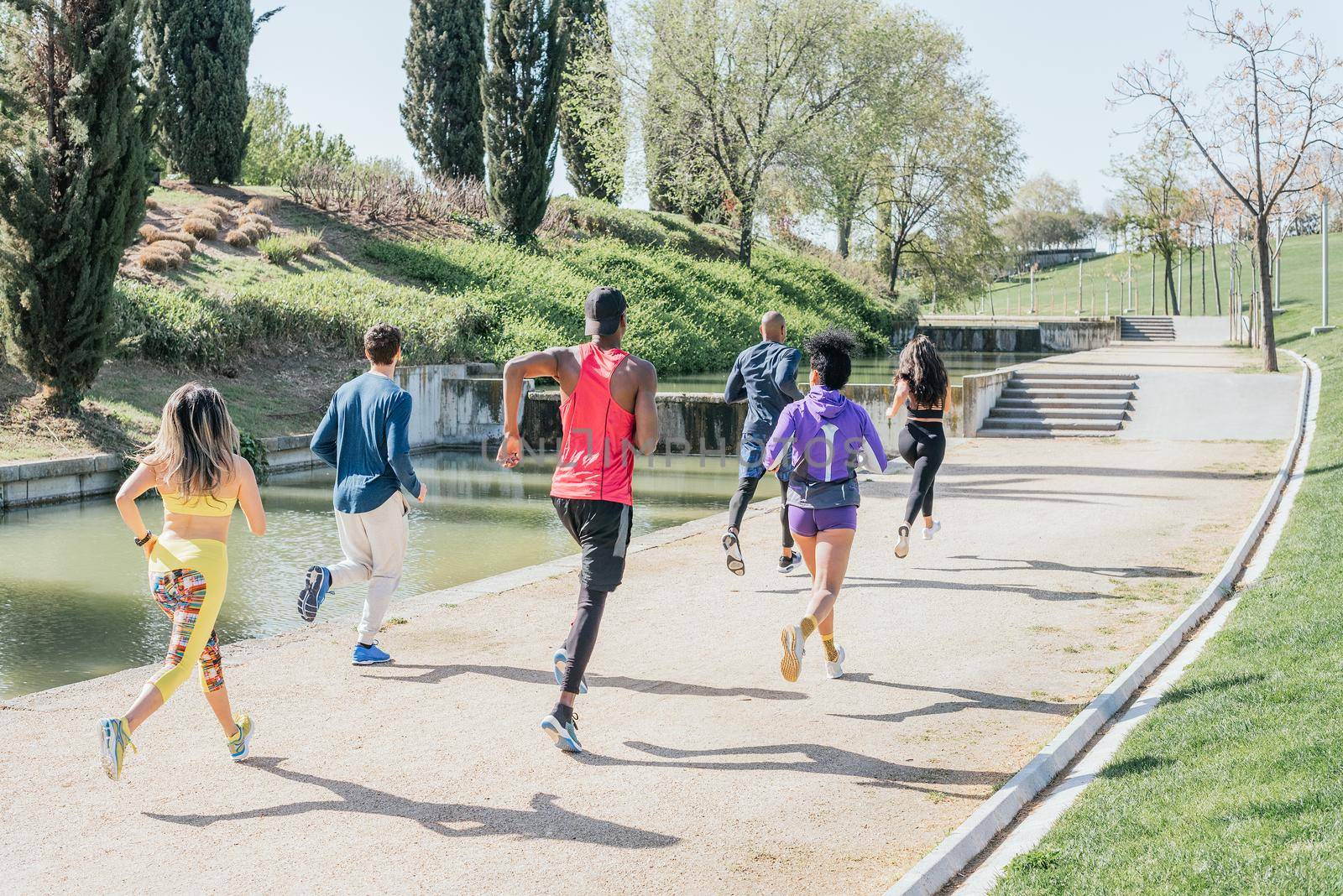 Group of runners training in a park. Rear view, back to camera. Happy and smiling.