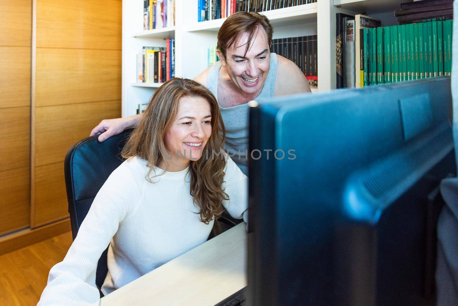 Middle-aged couple looking happy at computer at home. High quality photo