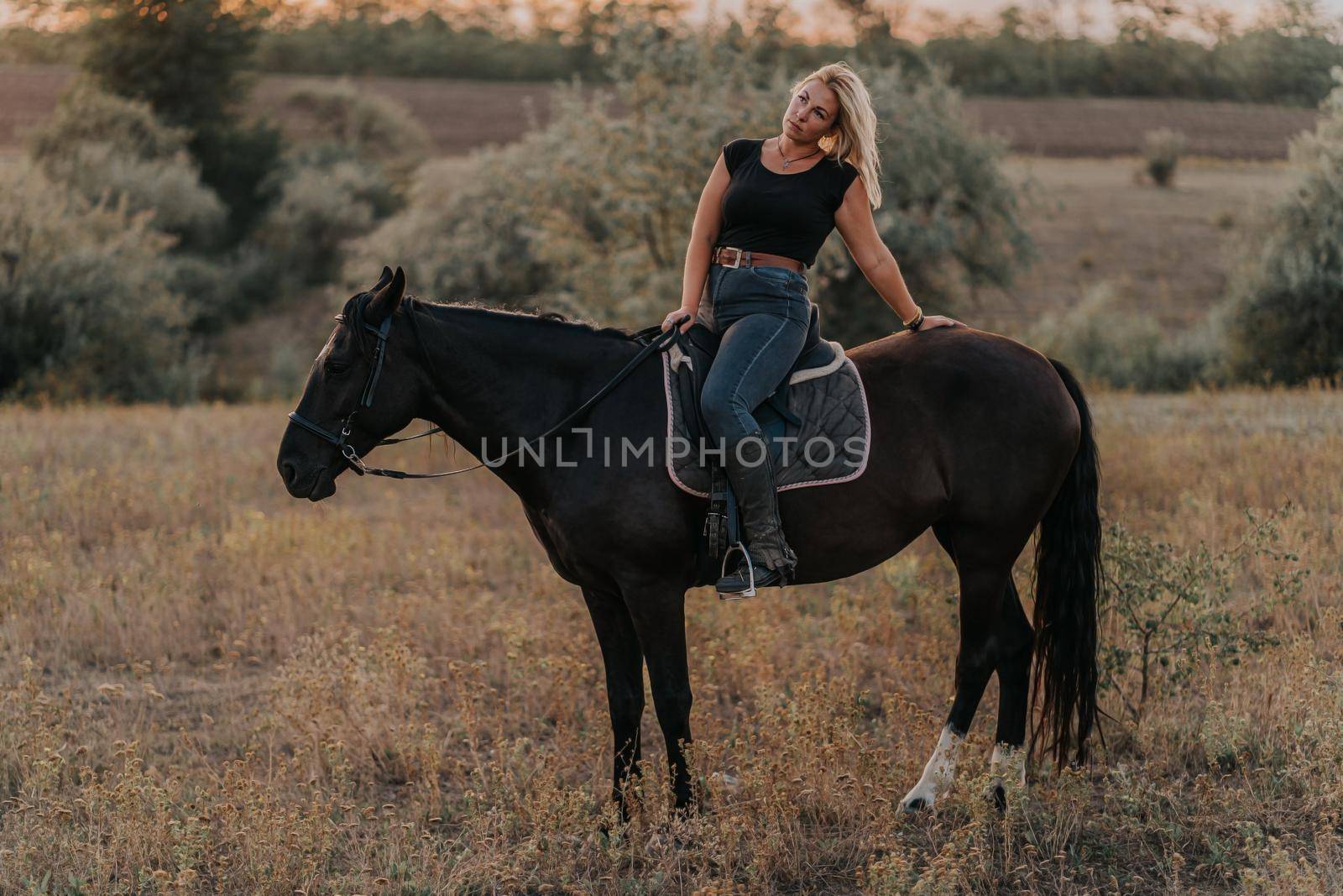 Pretty woman sitting on horse on nature background. Concept of love, friendship, farm animals. High quality photo
