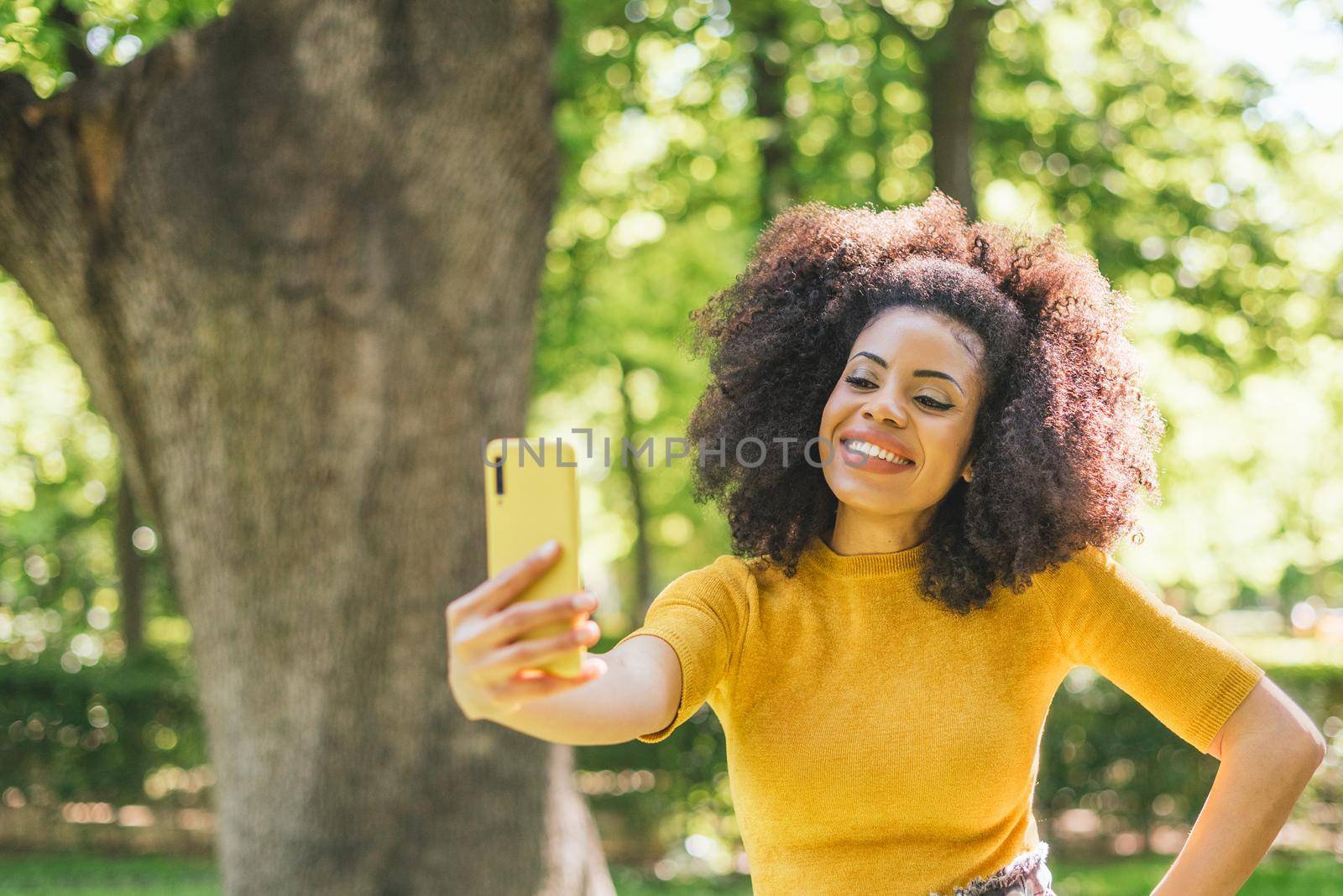 Pretty afro woman taking a selfie smiling. by ivanmoreno