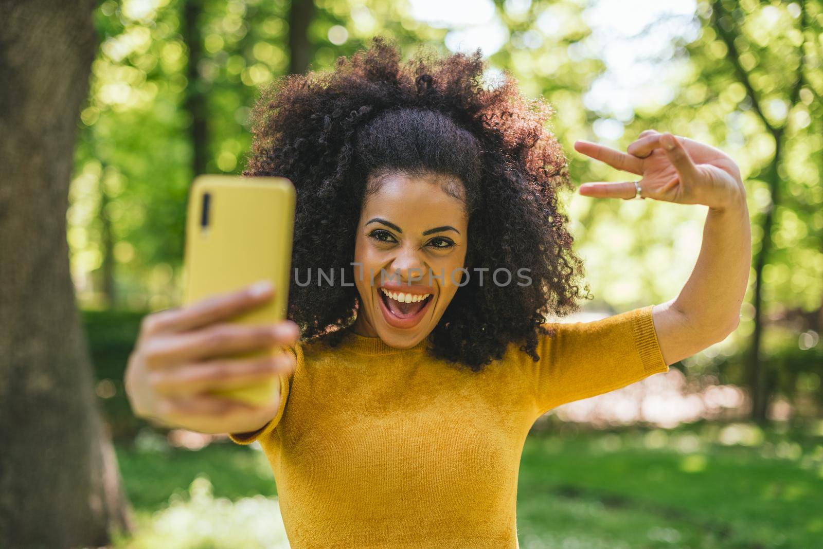 Pretty afro girl taking a selfie laughing. by ivanmoreno