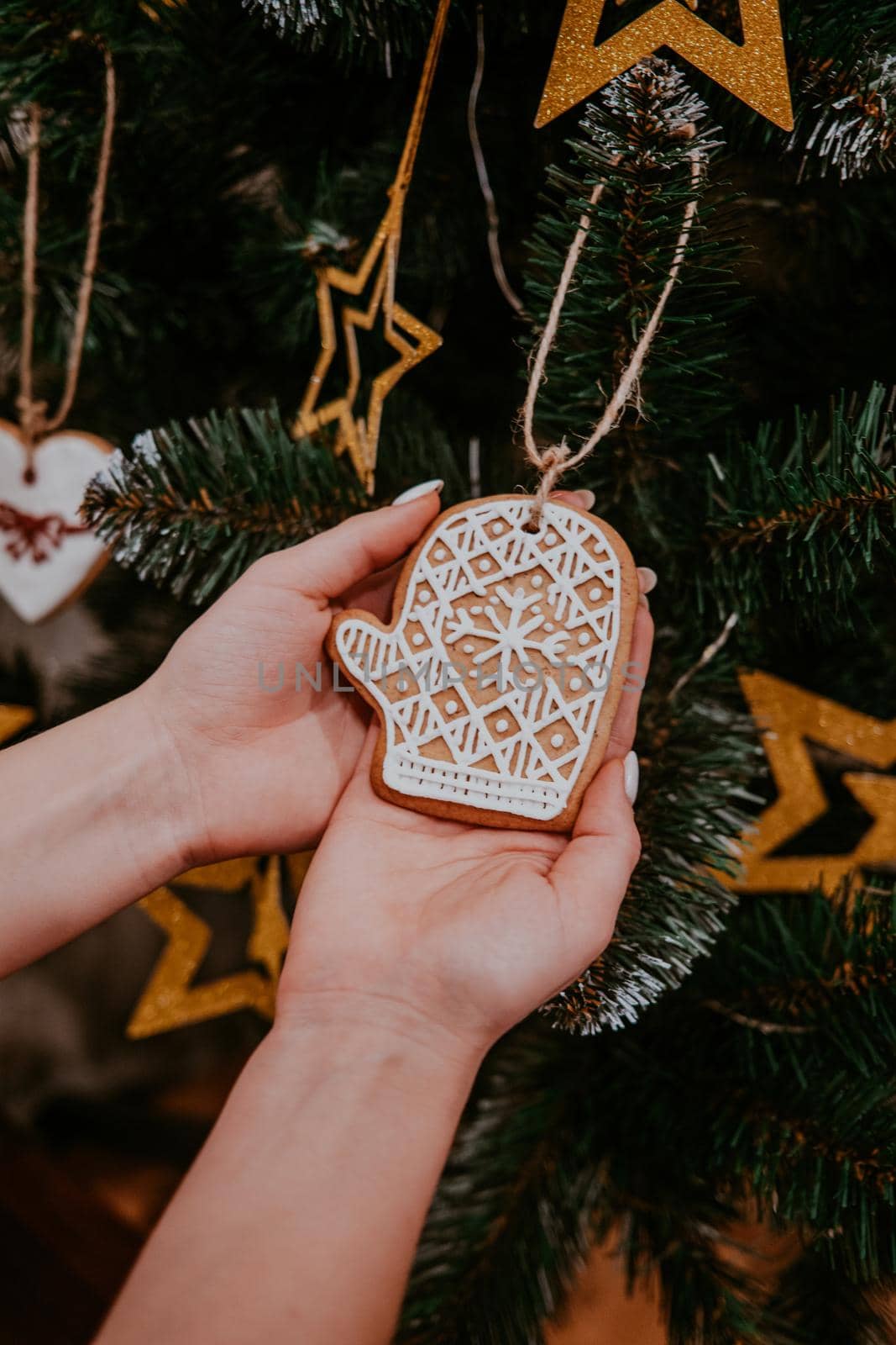 Woman decorating Christmas tree with gingerbread mitten cookie. Holiday concept. High quality photo