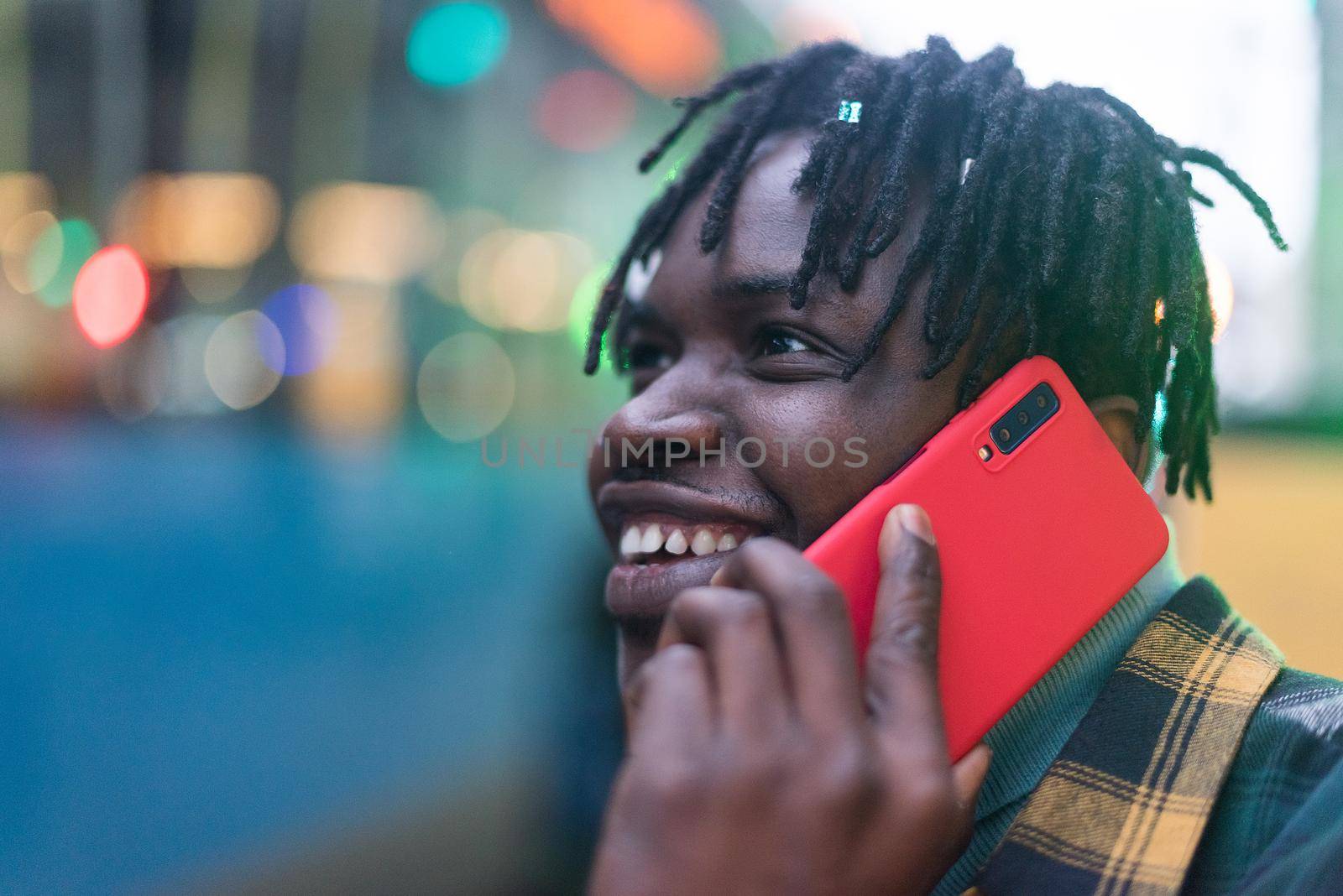 Smiling black guy talking on mobile in the city. Selective focus.