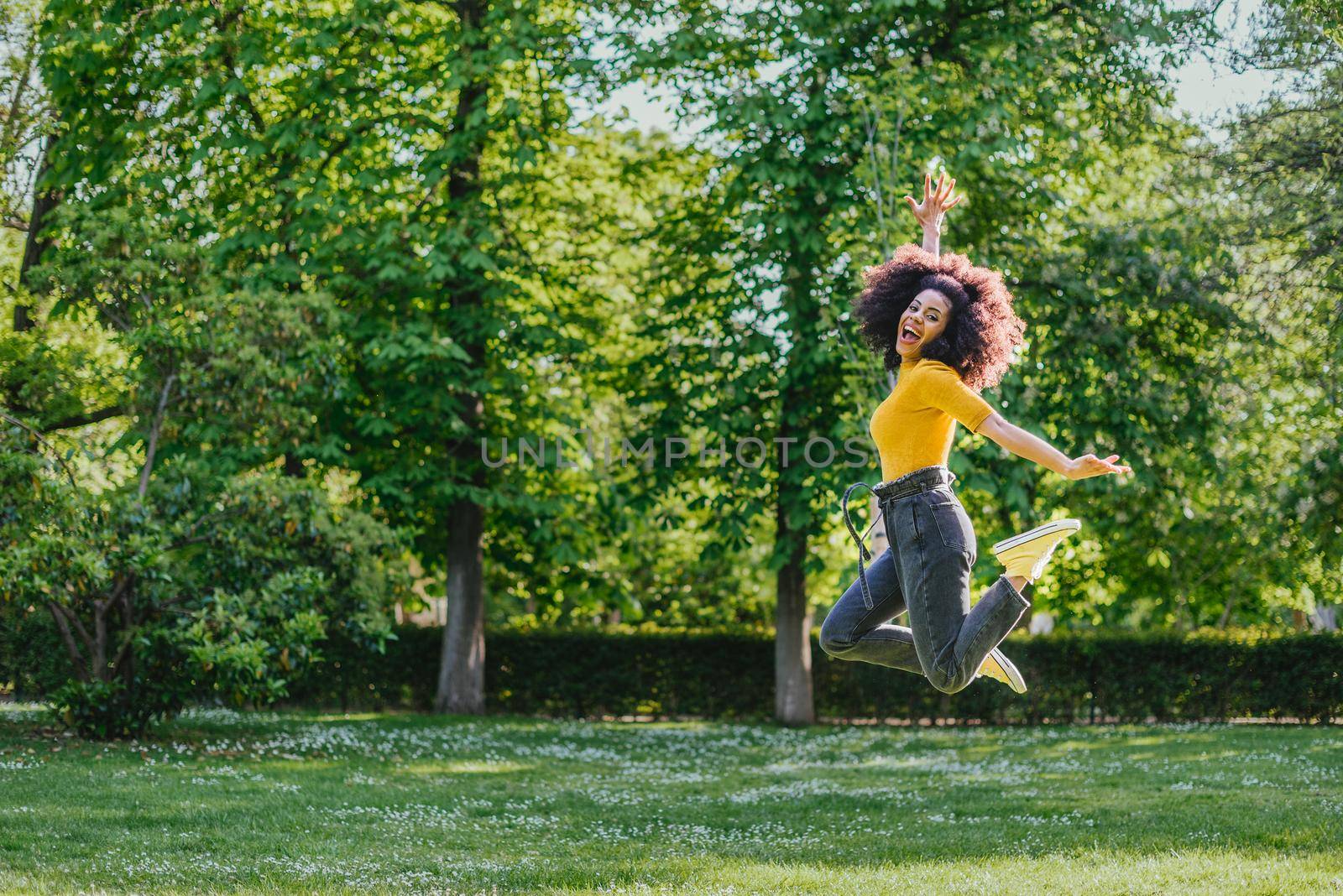 Pretty woman jumping happily in a garden. by ivanmoreno