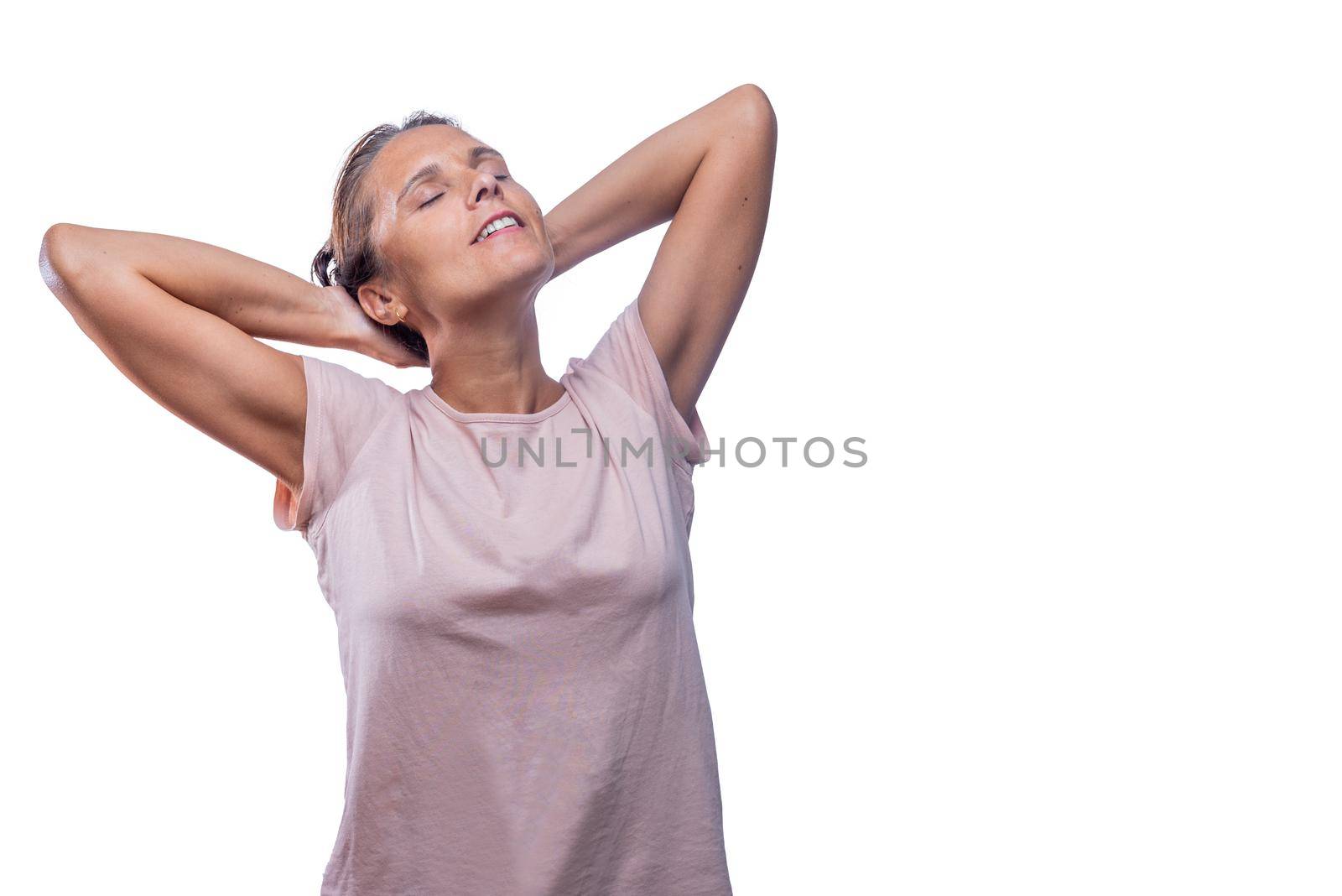 Front view of a relaxed adult woman standing with her hands behind head and eyes closed on a white background with copy space.