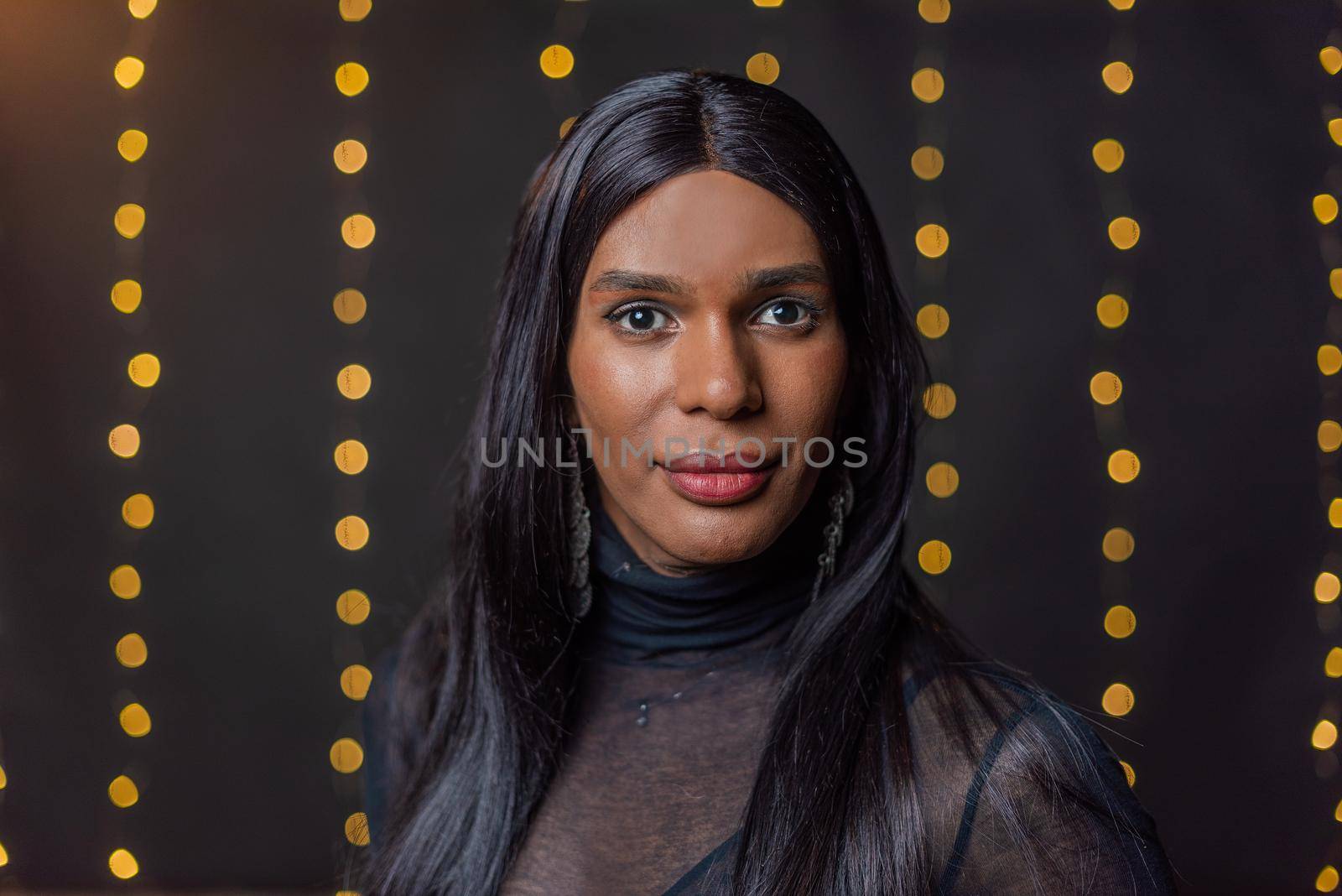 A transgender person looking at camera with blurred light background by ivanmoreno