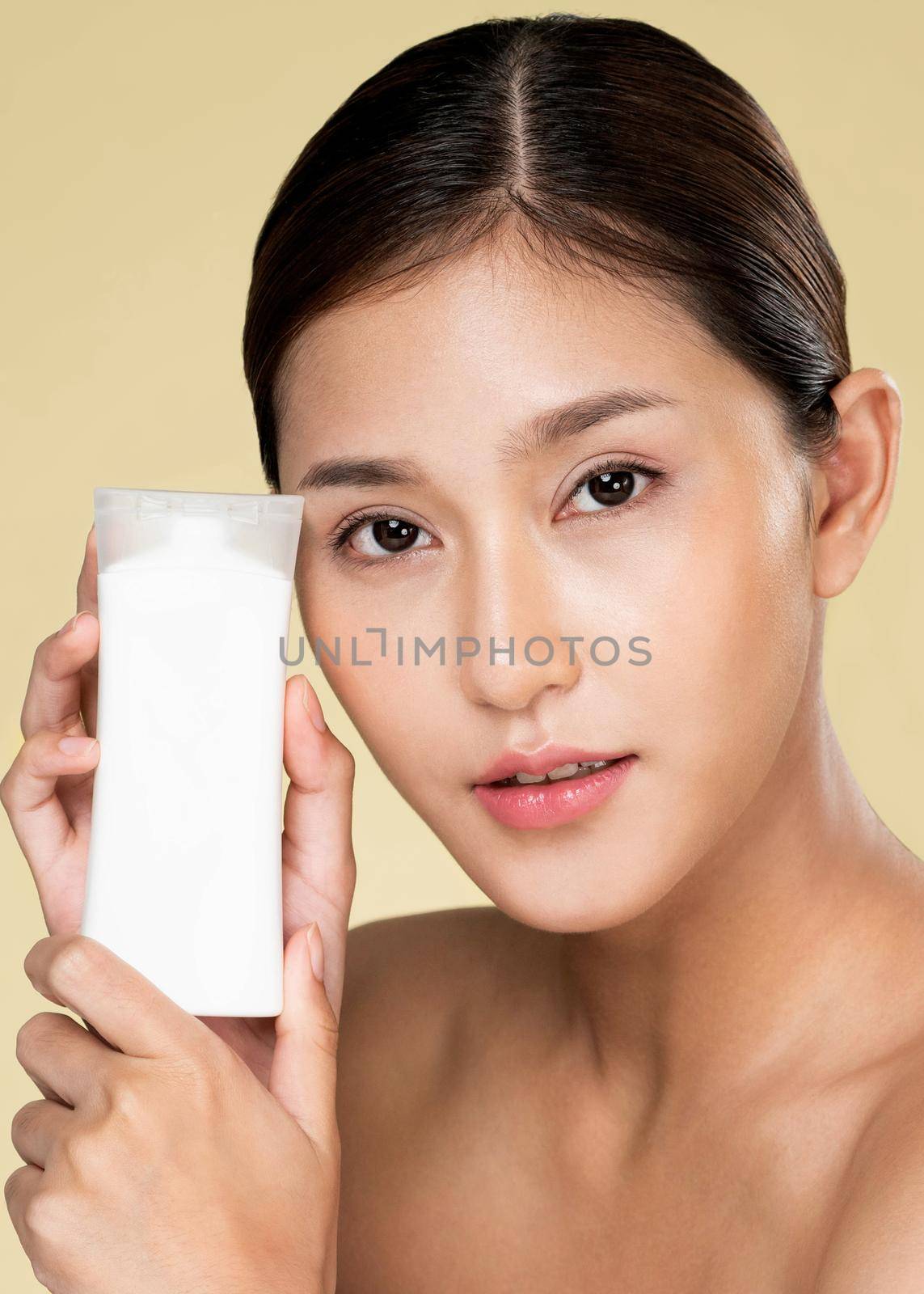 Closeup ardent woman smiling holding mockup product for advertising text place, light grey background. Concept of healthcare for skin, beauty care product for advertising.