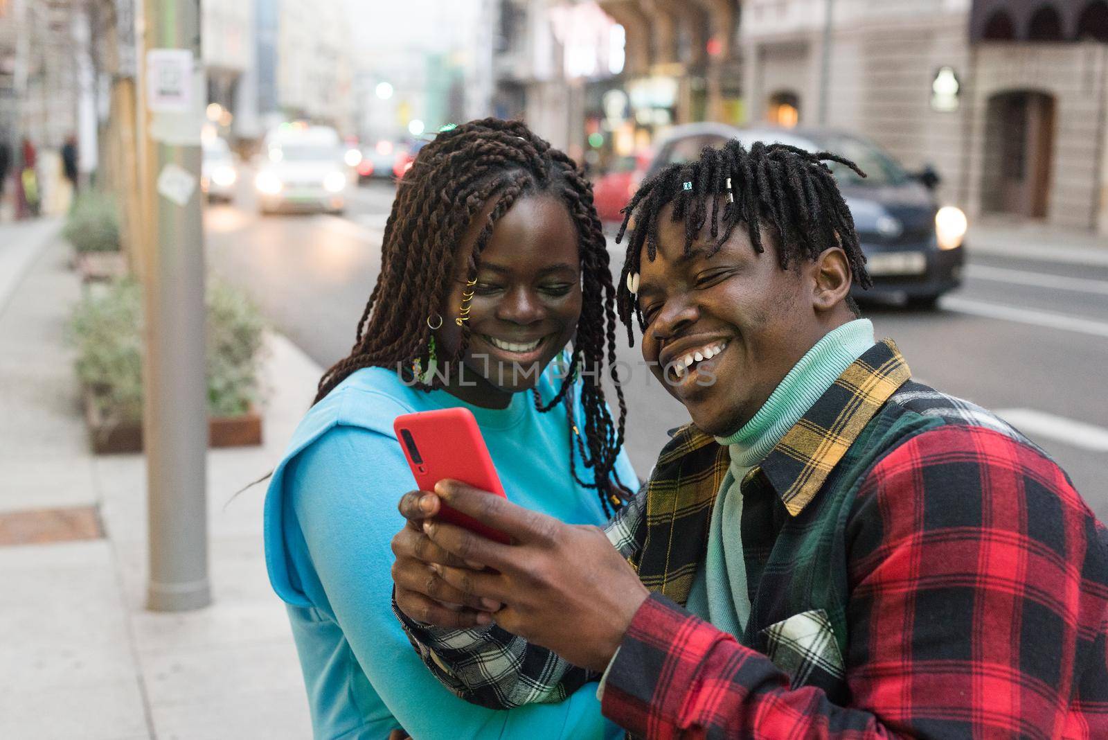 Smiling black couple looking at mobile on the street. Selective focus.