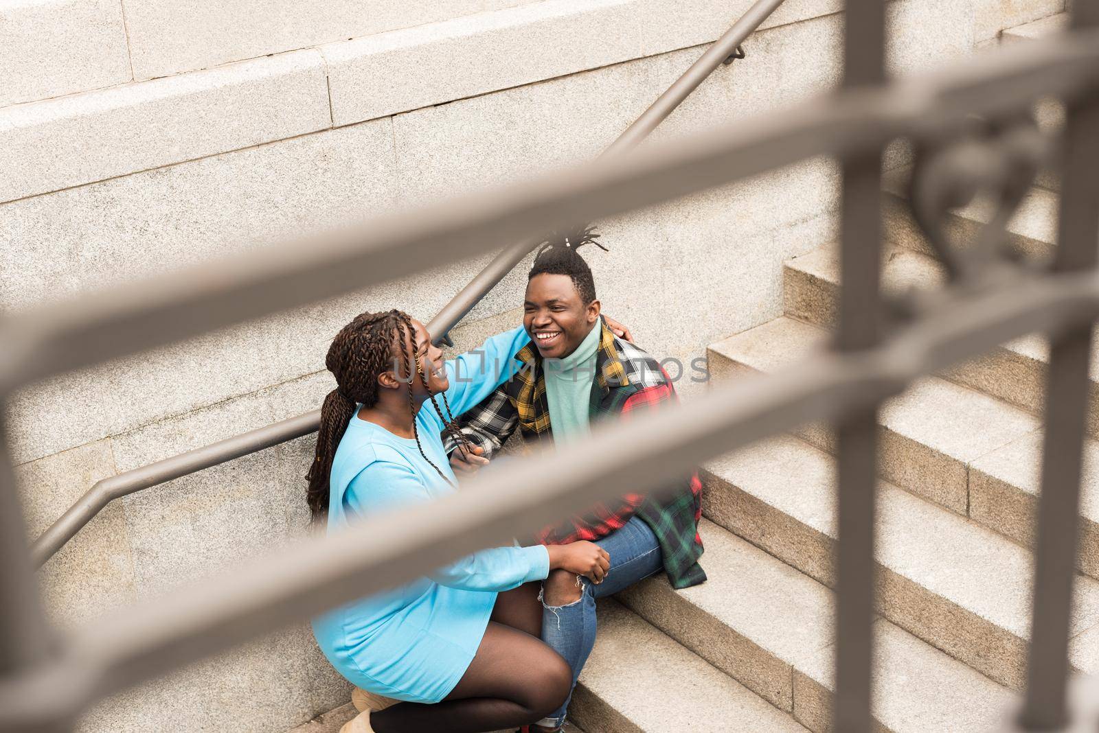 Black couple sitting on a stairs in the city. Selective focus.