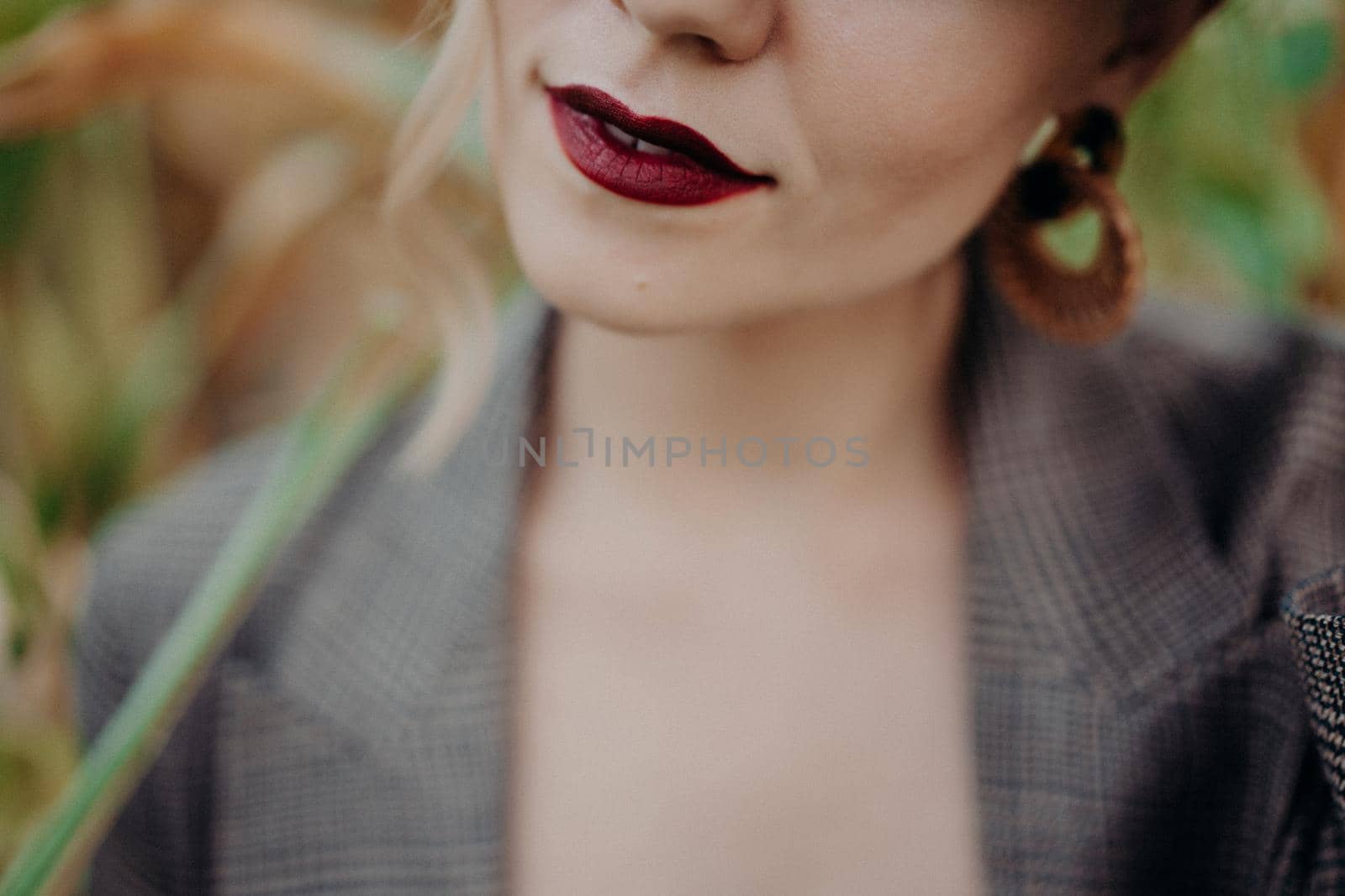 Dark red lips of trendy unrecognizable woman in jacket at natural corn background. High quality photo