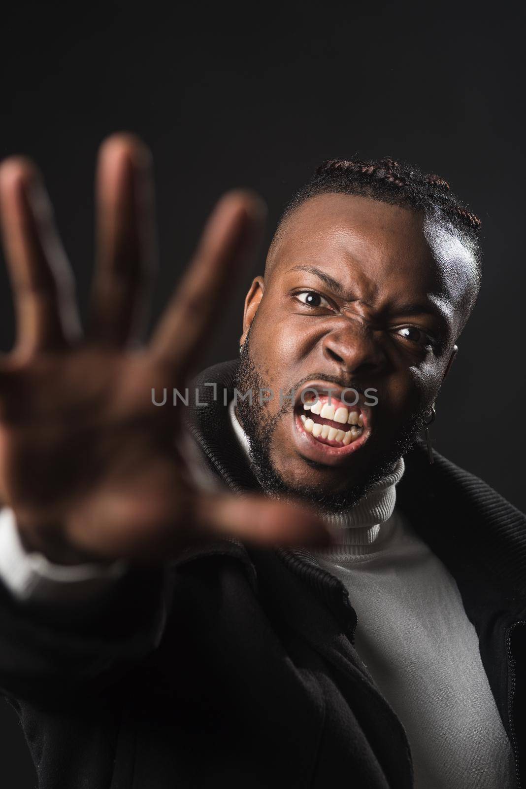 Very angry black man telling you to stop with an open hand, fighting for his rights. Close up. Black background.