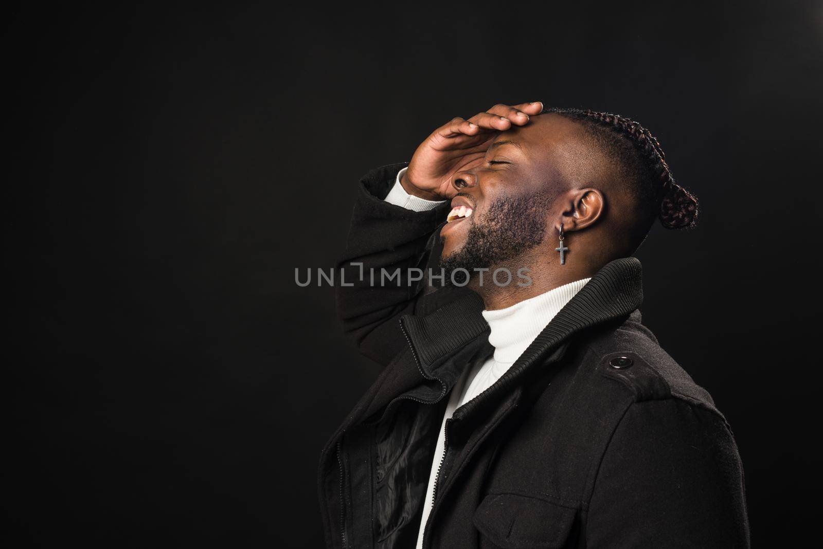 Black man in profile laughing with hand on face. by ivanmoreno